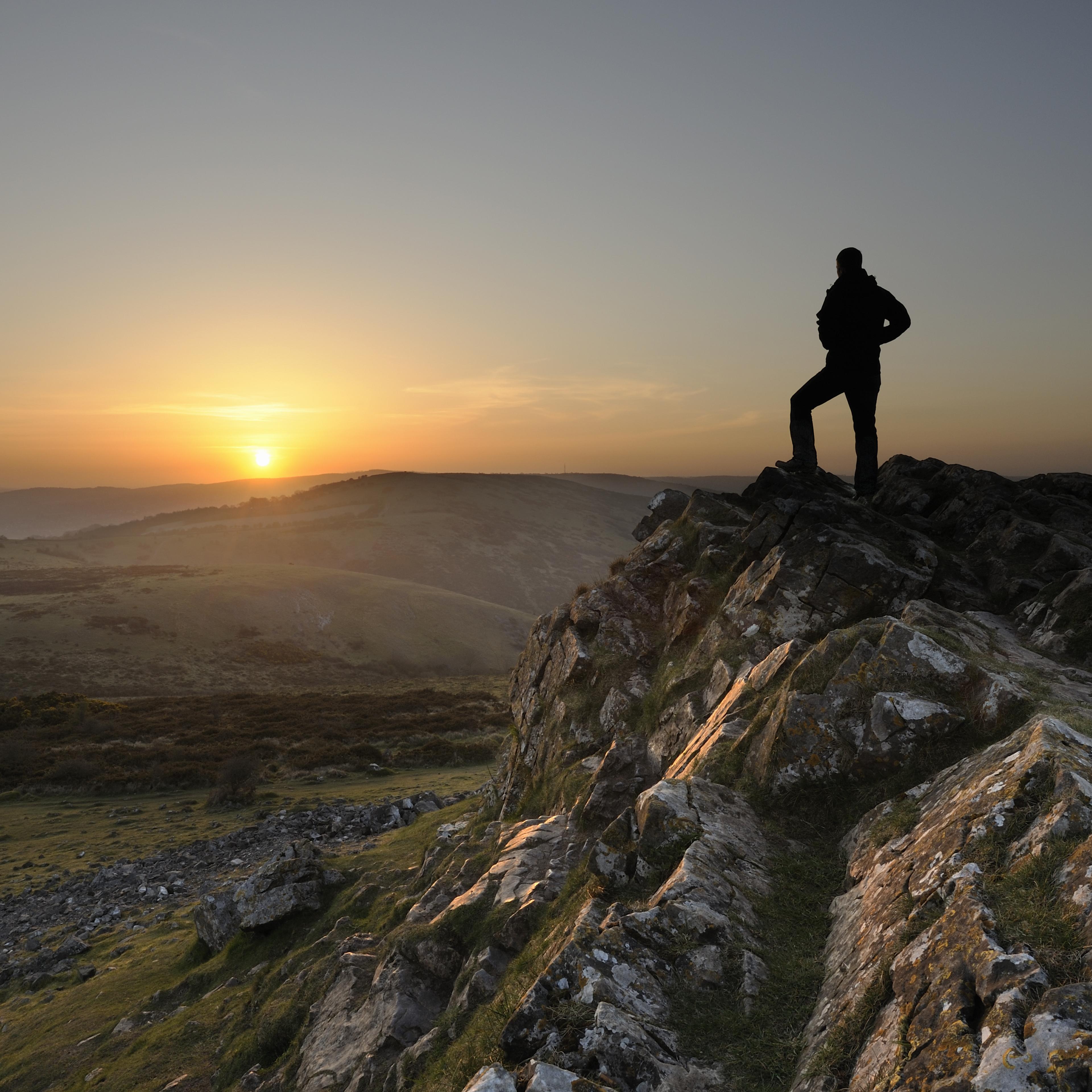man-standing-mountain-peak-sunset
