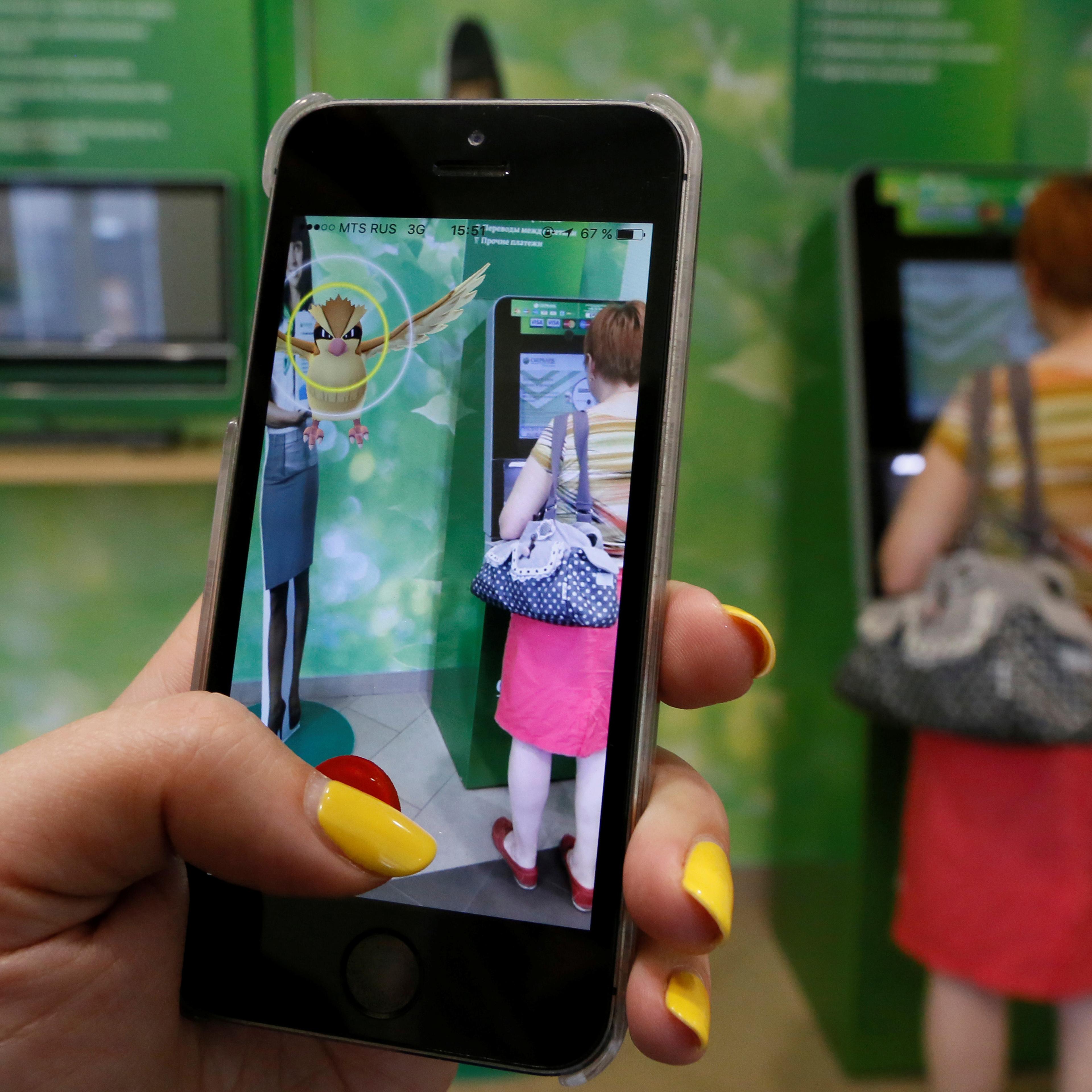 Woman plays augmented reality mobile game "Pokemon Go" by Nintendo at branch of Sberbank in central Krasnoyarsk