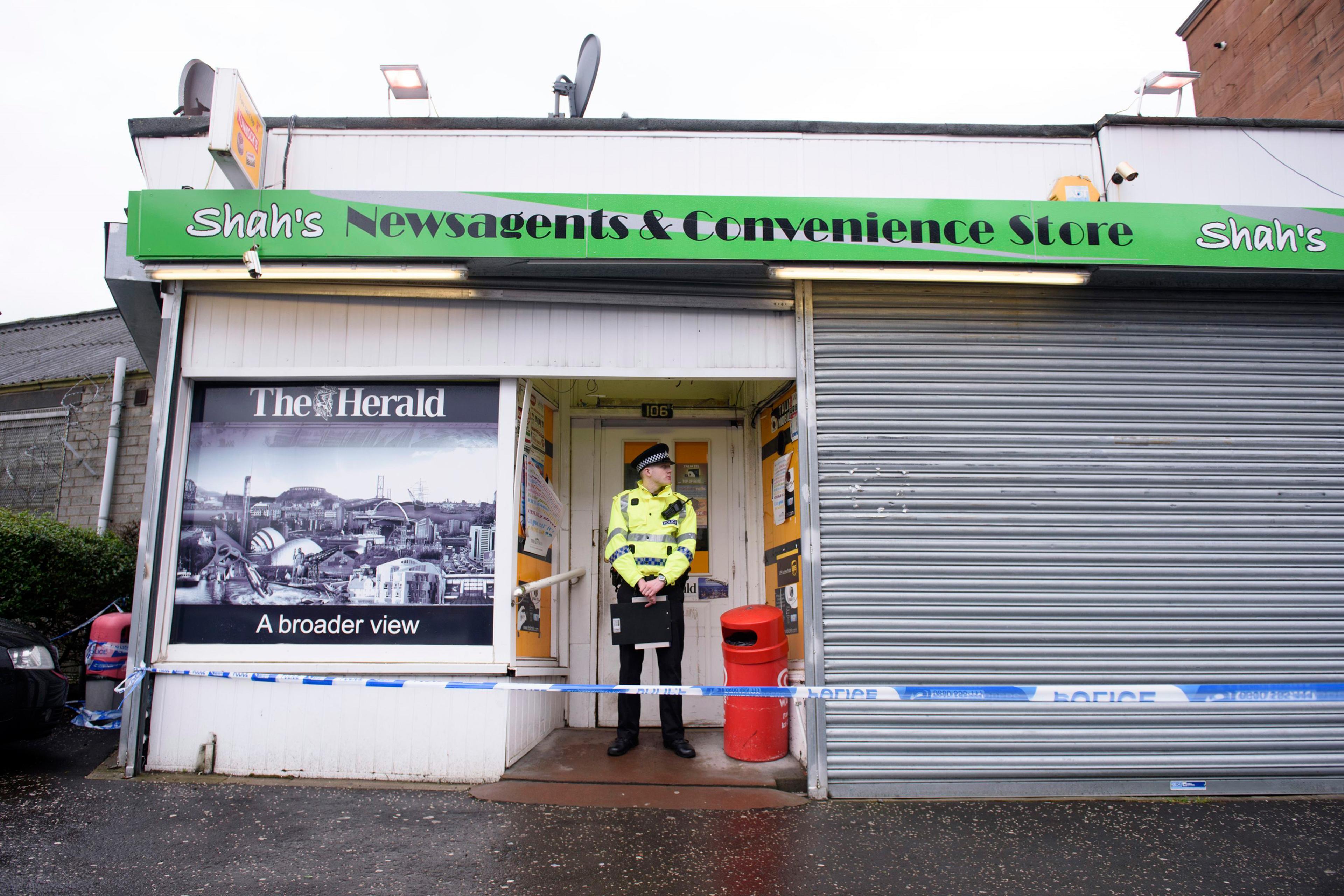 A police officer stands outside the shop where Asad Shah worked in Glasgow, Saturday March 26, 2016. Scottish police say the killing of a Muslim shopkeeper who wished Christians a happy Easter is being investigated as “religiously prejudiced.” Vigils wer