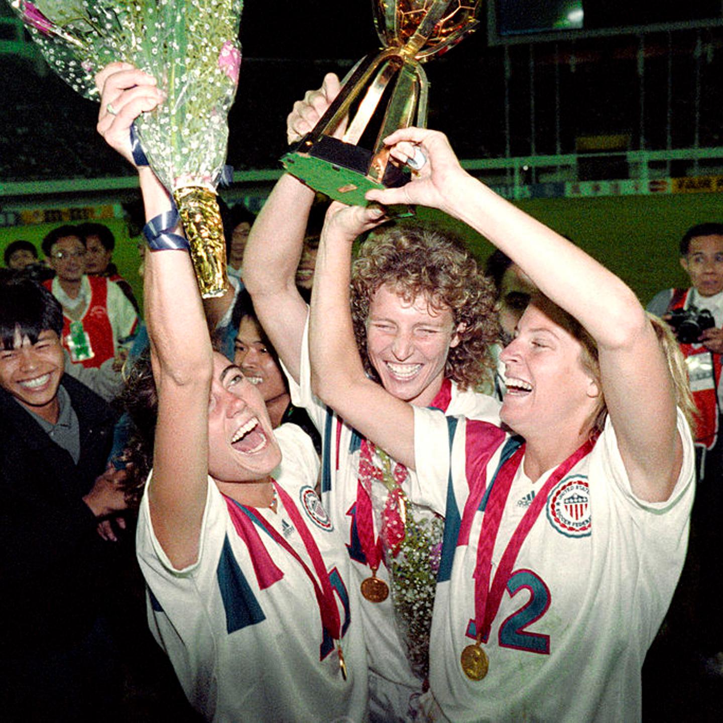 Michelle Akers-Stahl, who scored two goals for the U.S. to win what would be the first FIFA Women’s World Cup on Nov. 30, 1991, holds the trophy with teammates Julie Foudy, left, and Carin Jennings, right.
