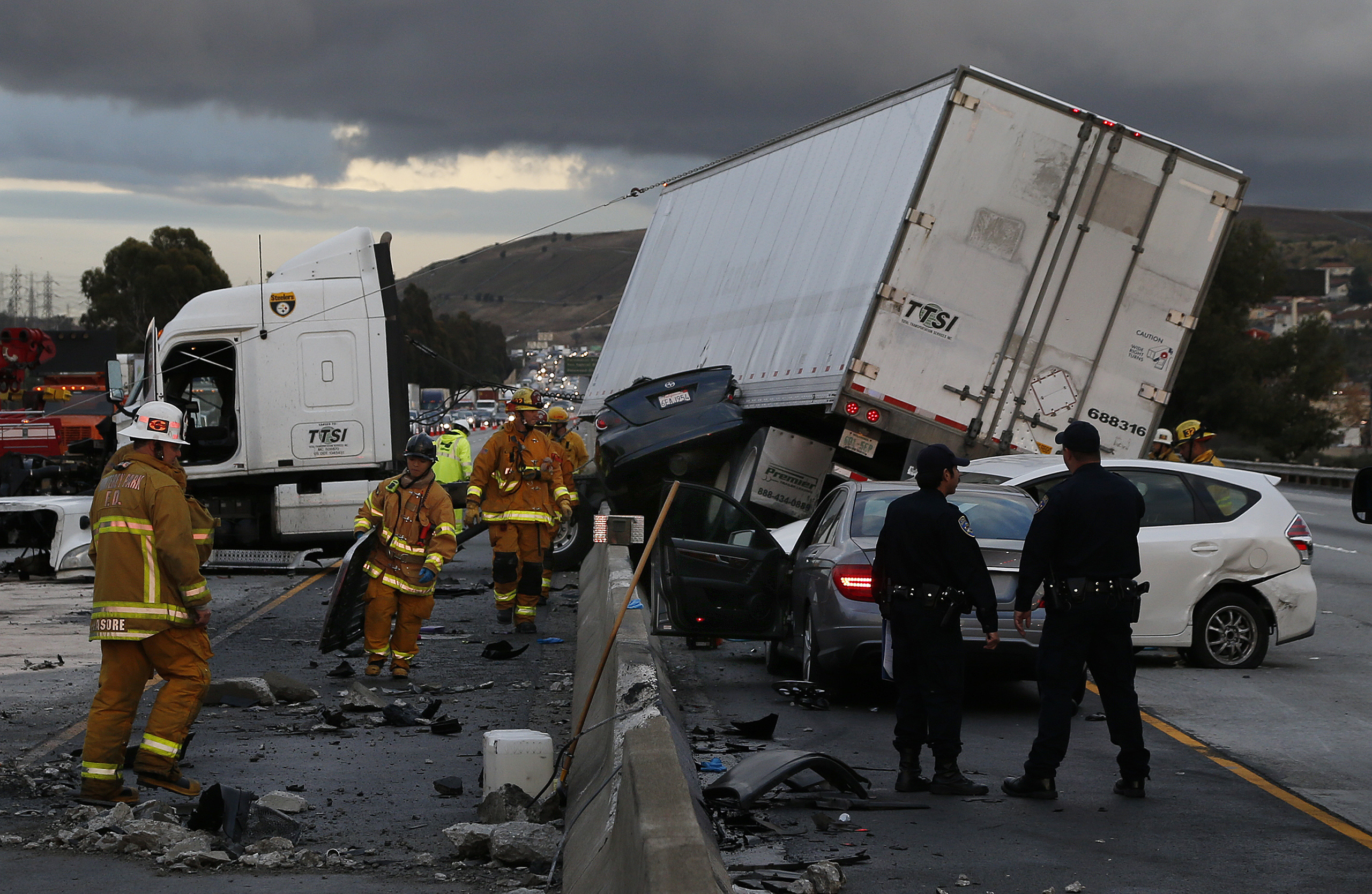 Firefighters and rescue personnel are on scene after a big rig crashed through the center divider crushing a car underneath and causing four other vehicles to collide on the rain slicked 60 freeway near the Garfield Exit in Monterey Park, Calif. on Janua