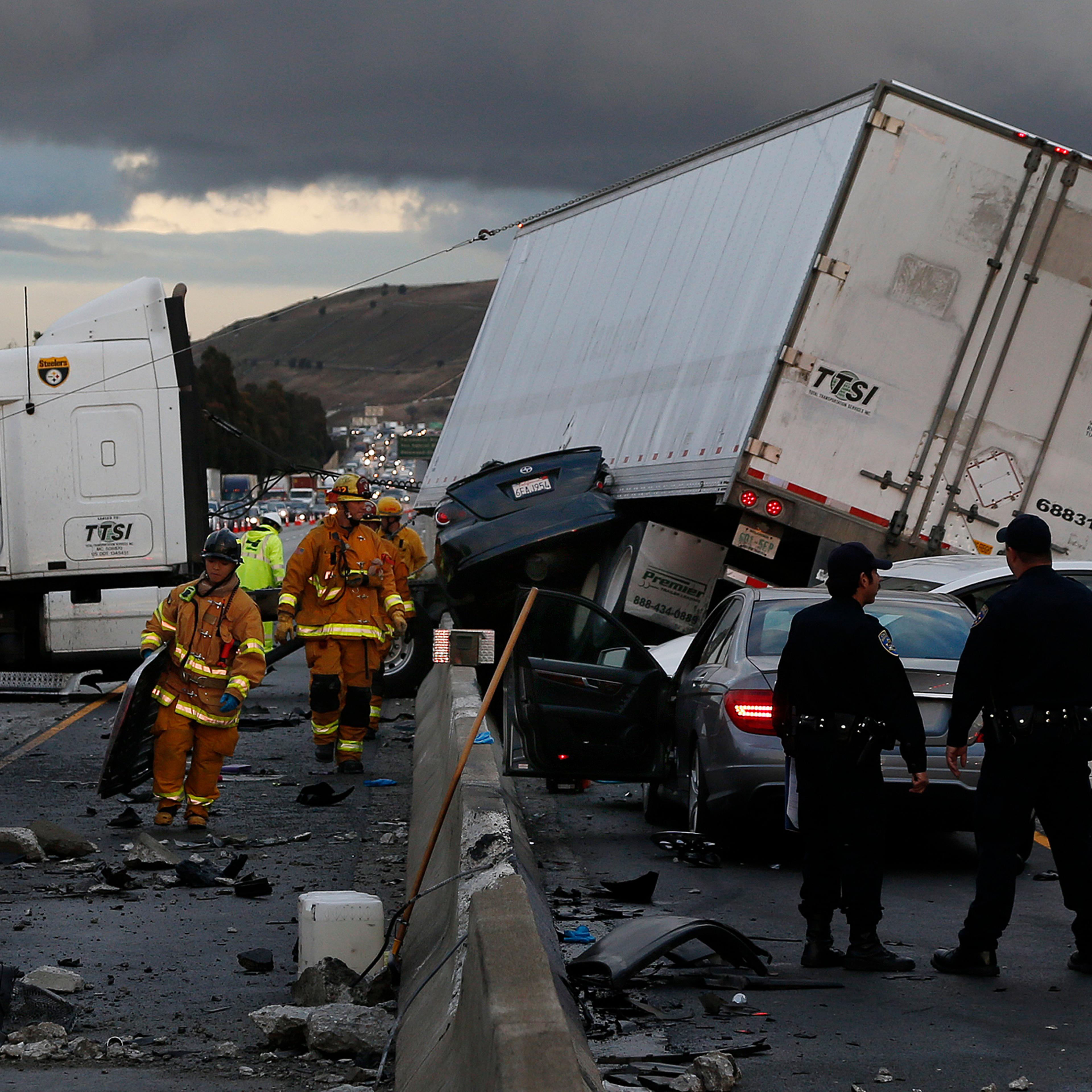 Firefighters and rescue personnel are on scene after a big rig crashed through the center divider crushing a car underneath and causing four other vehicles to collide on the rain slicked 60 freeway near the Garfield Exit in Monterey Park, Calif. on Janua
