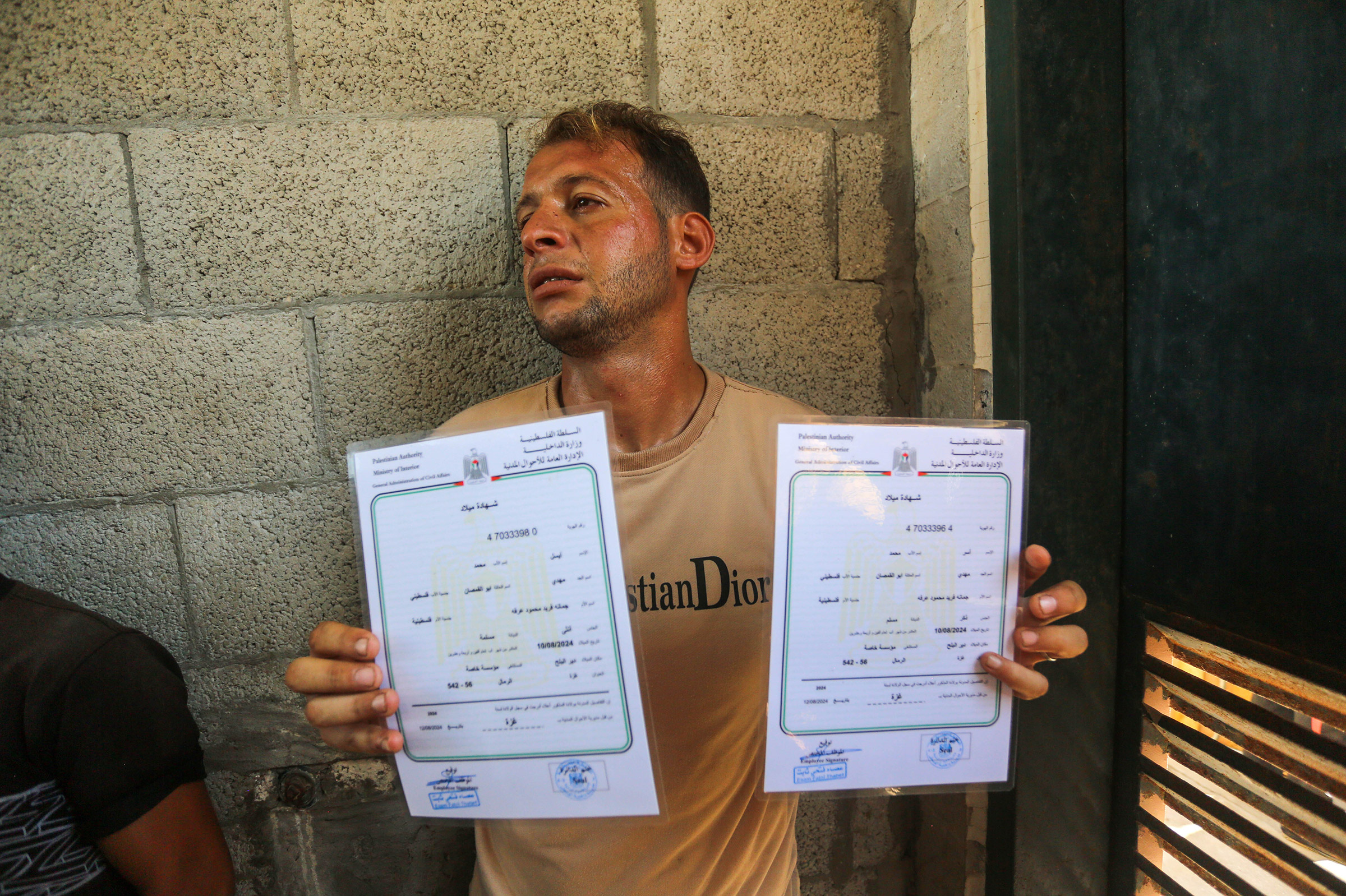 Mohammed Abu al-Qumsan shows the birth certificates of his twins after learning that his wife, 4-day-old twins babies and mother-in-law had died in an Israeli airstrike, at the morgue of Al-Aqsa Martyrs Hospital in Deir Al Balah, Gaza on Aug. 13, 2024.