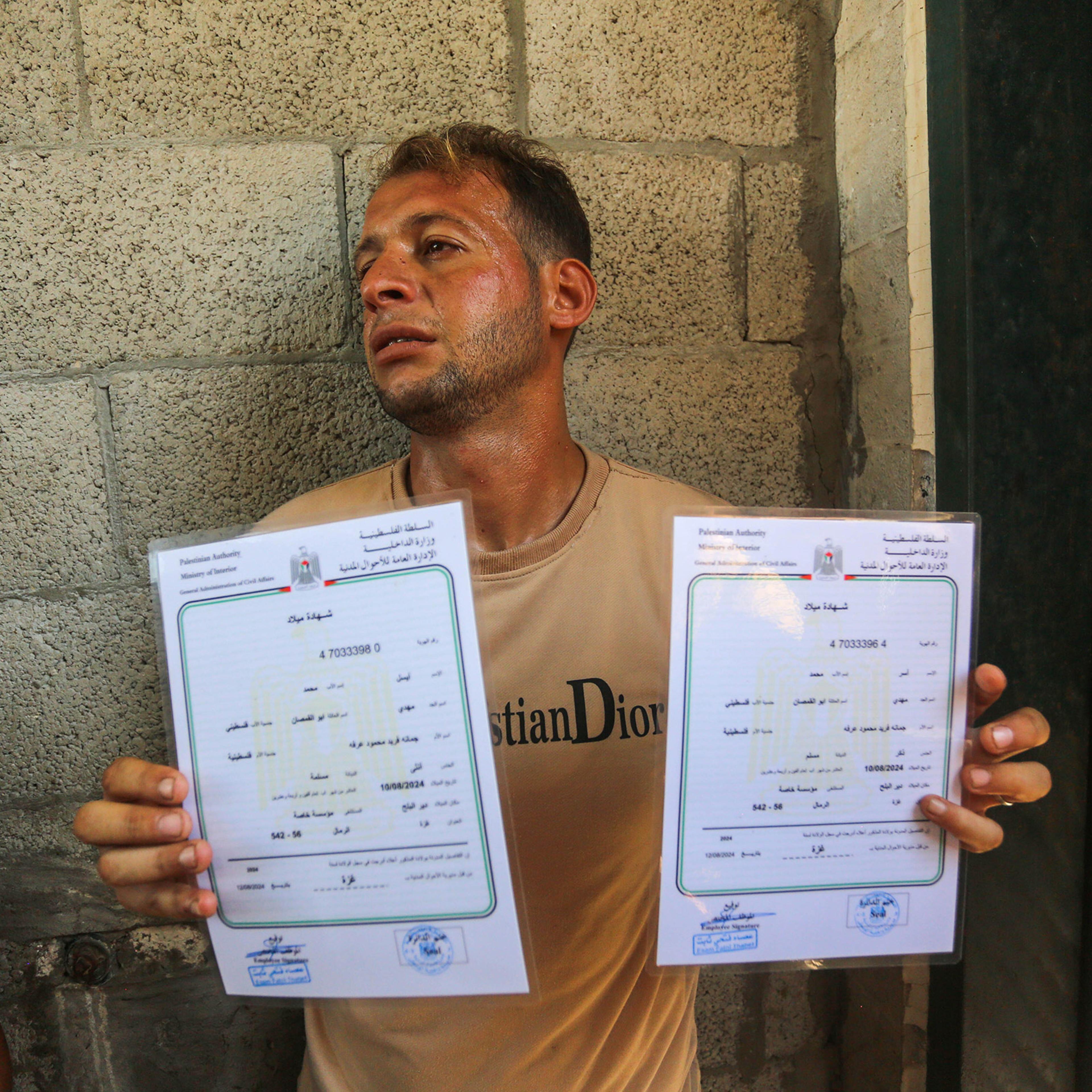 Mohammed Abu al-Qumsan shows the birth certificates of his twins after learning that his wife, 4-day-old twins babies and mother-in-law had died in an Israeli airstrike, at the morgue of Al-Aqsa Martyrs Hospital in Deir Al Balah, Gaza on Aug. 13, 2024.