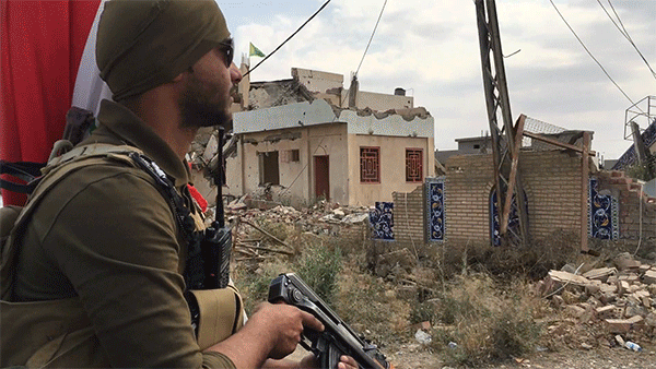 A local militia  fighter rides past destroyed buildings in the town of Bashir, Iraq, May 10, 2016.