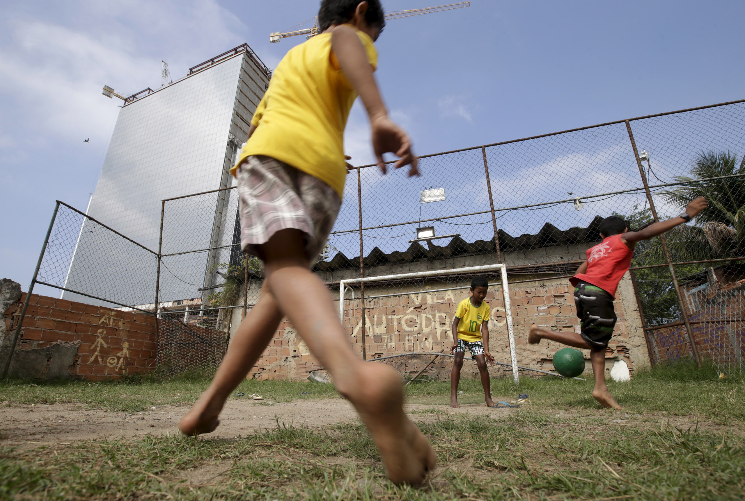 Children play soccer in the Vila Autodromo slum in Rio de Janeiro, Brazil, July 28, 2015. As sports arenas rise up around them and neighbours' houses are demolished, around 50 families remain in Vila Autodromo, a favela bordering the Olympic Park in Rio 