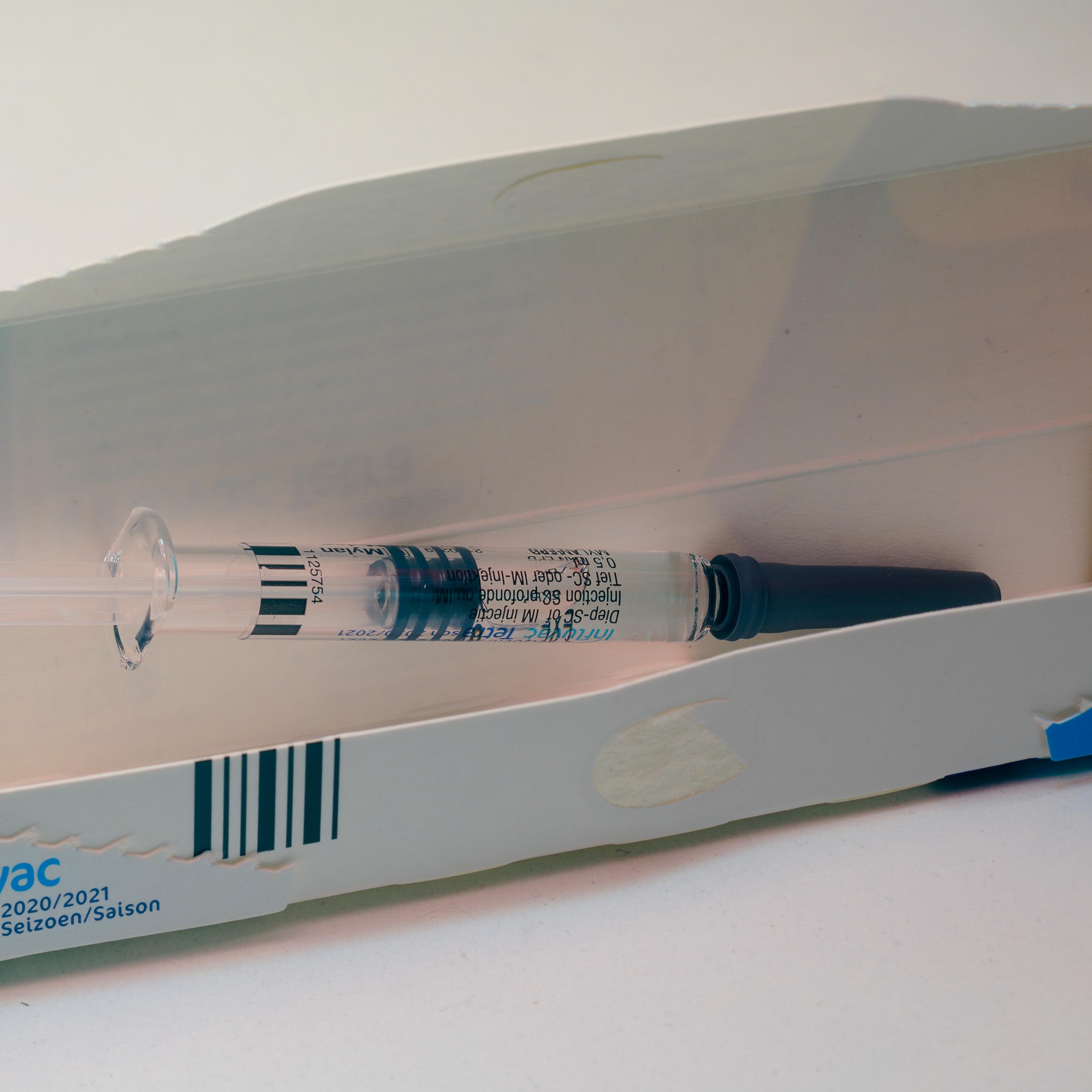 A Flu Vaccine Syringe Rests On A Table