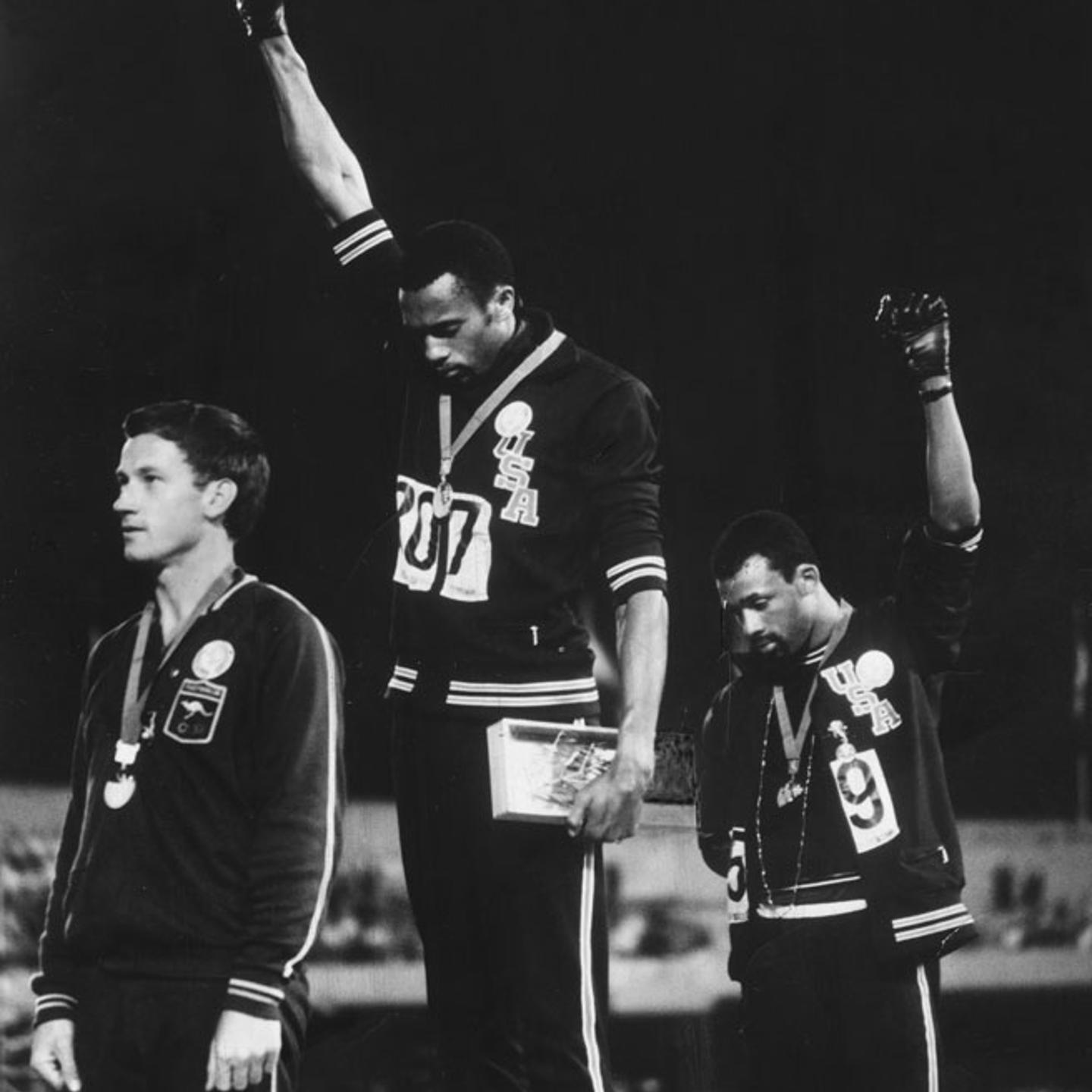 Tommie Smith (center) and John Carlos (right) raise black-gloved fists during the American national anthem; Australian silver medalist Peter Norman, who supported their protest, is at left.