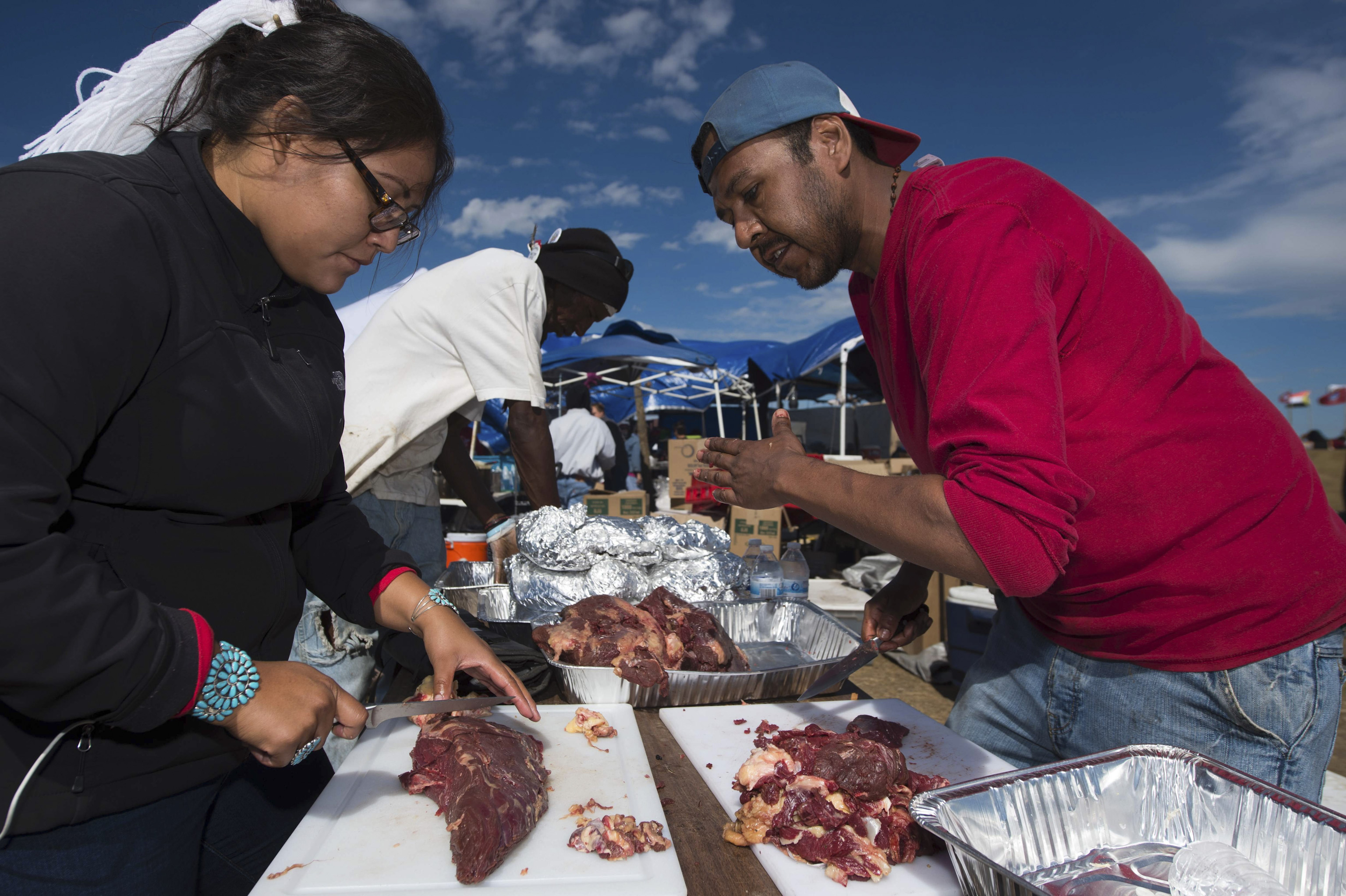 Lamar Armstrong of the Mojave Paiute, right, instructs graduate student Tyesha Ignacio of the Najavo Nation how to prepare donated bison meat in the main kitchen area of the Standing Rock Sioux protest encampment near Cannon Ball, North Dakota on Sept. 3
