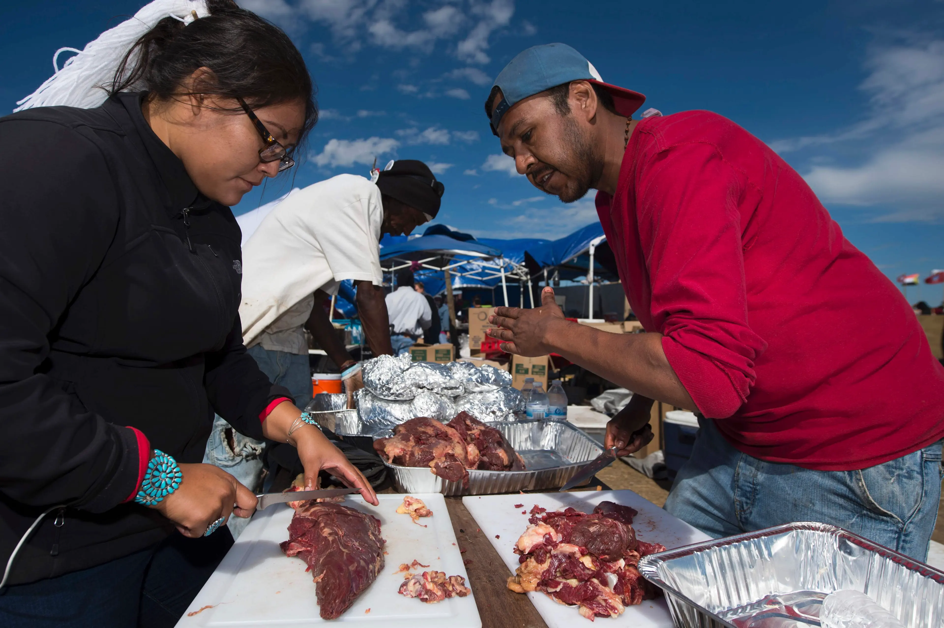 Lamar Armstrong of the Mojave Paiute, right, instructs graduate student Tyesha Ignacio of the Najavo Nation how to prepare donated bison meat in the main kitchen area of the Standing Rock Sioux protest encampment near Cannon Ball, North Dakota on Sept. 3