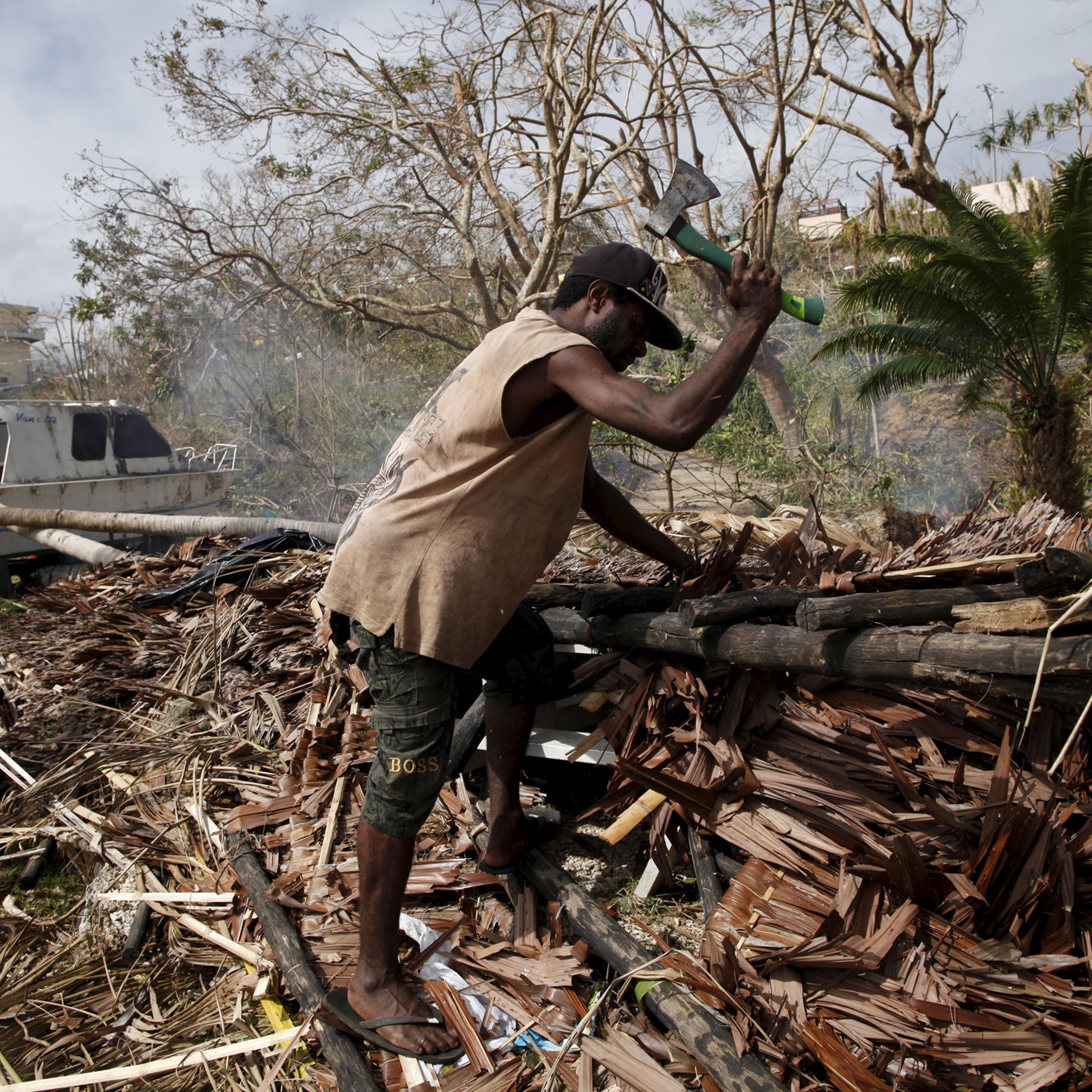 A worker chops up fallen trees next to a destroyed boat at a resident's compound days after Cyclone Pam in Port Vila, capital city of the Pacific island nation of Vanuatu March 19, 2015.