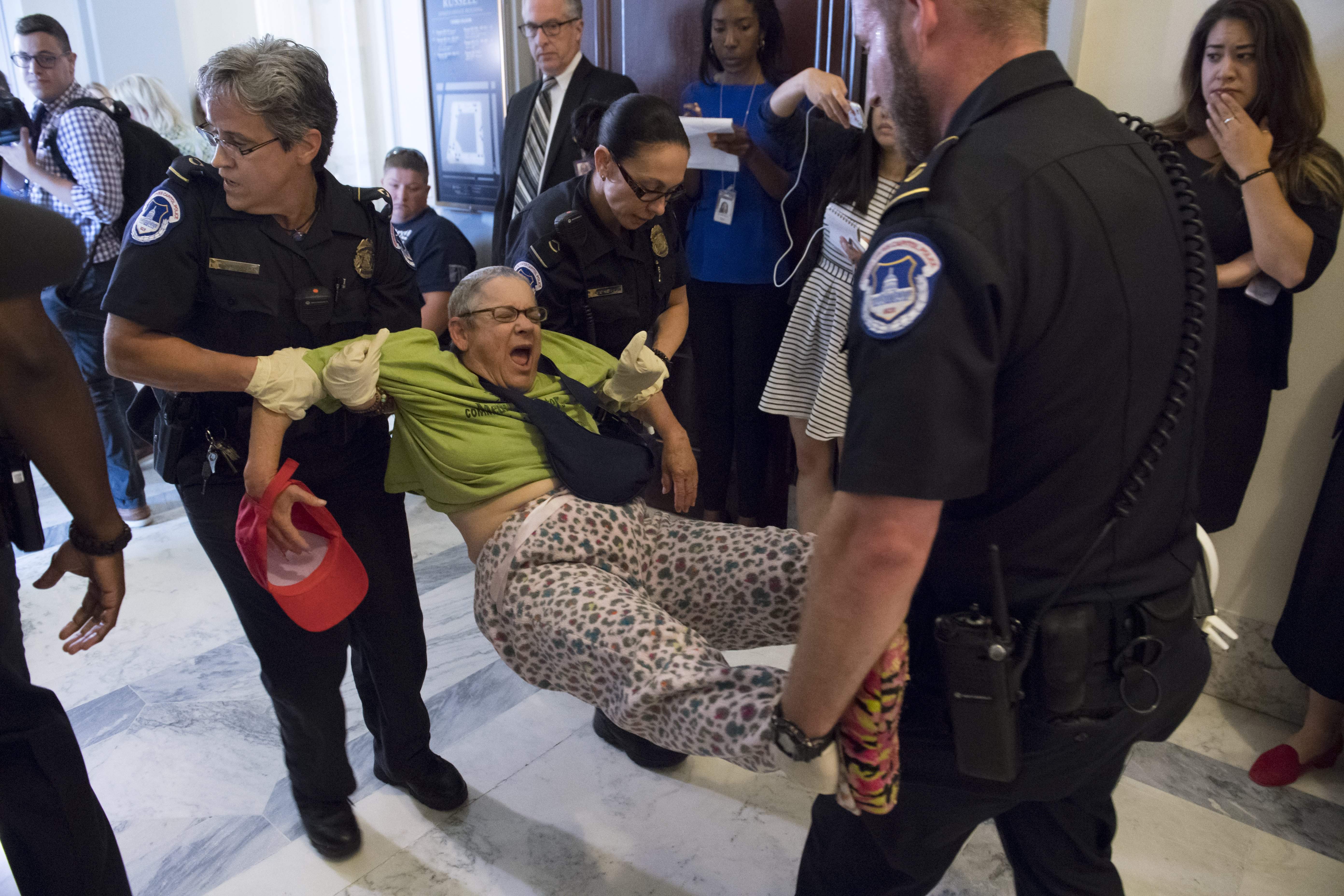 US Capitol Police arrest a protestor against the Senate Republican's draft healthcare bill outside the office of Senate Majority Leader Mitch McConnell, Republican of Kentucky, on Capitol Hill in Washington, DC, June 22, 2017.