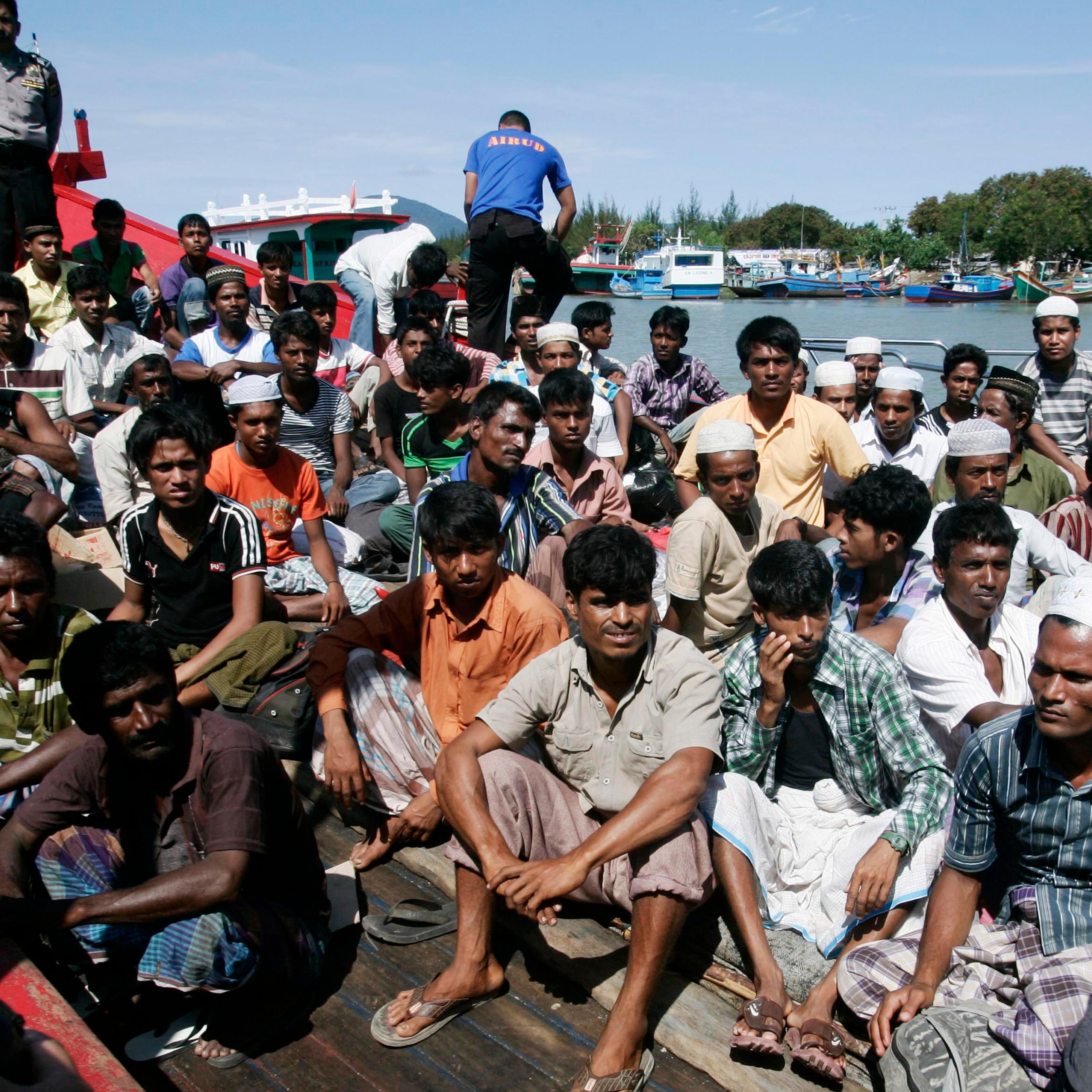 Ethnic Rohingya refugees from Myanmar sit on a wooden boat as they wait for transportation to a temporary shelter in Aceh Besar after arriving at Lampulo habour