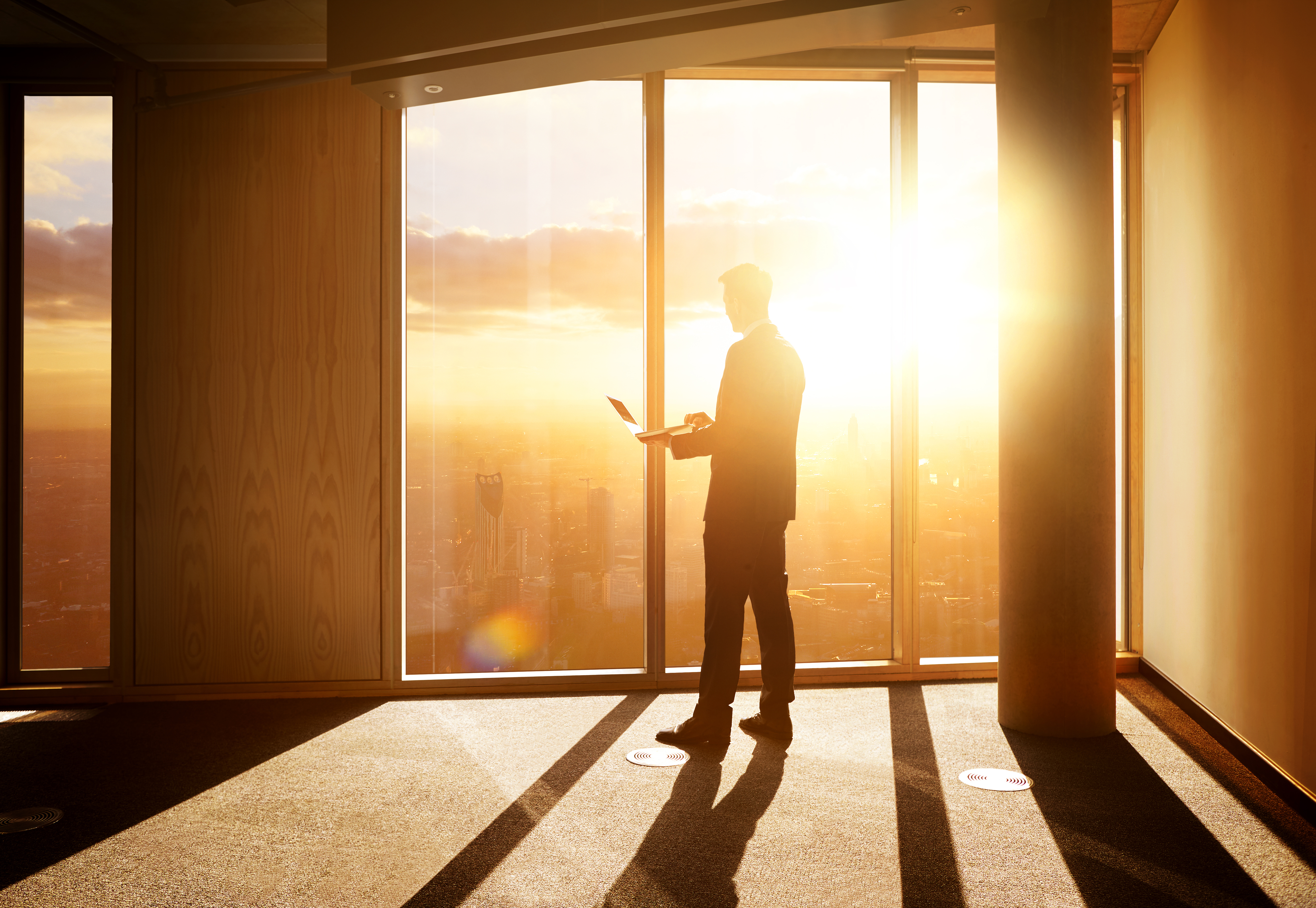 Businessman looking out over the city at sunrise.