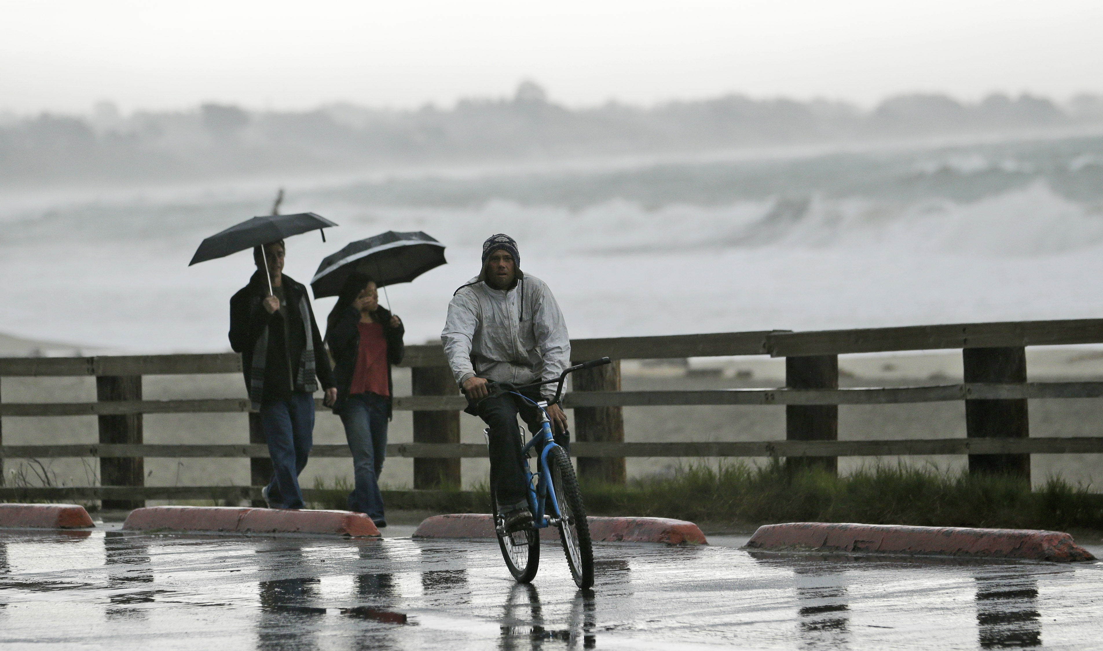 Visitors shield themselves from the rain along the beach at Seacliff State Beach on Feb. 6, 2015, in Aptos, Calif.