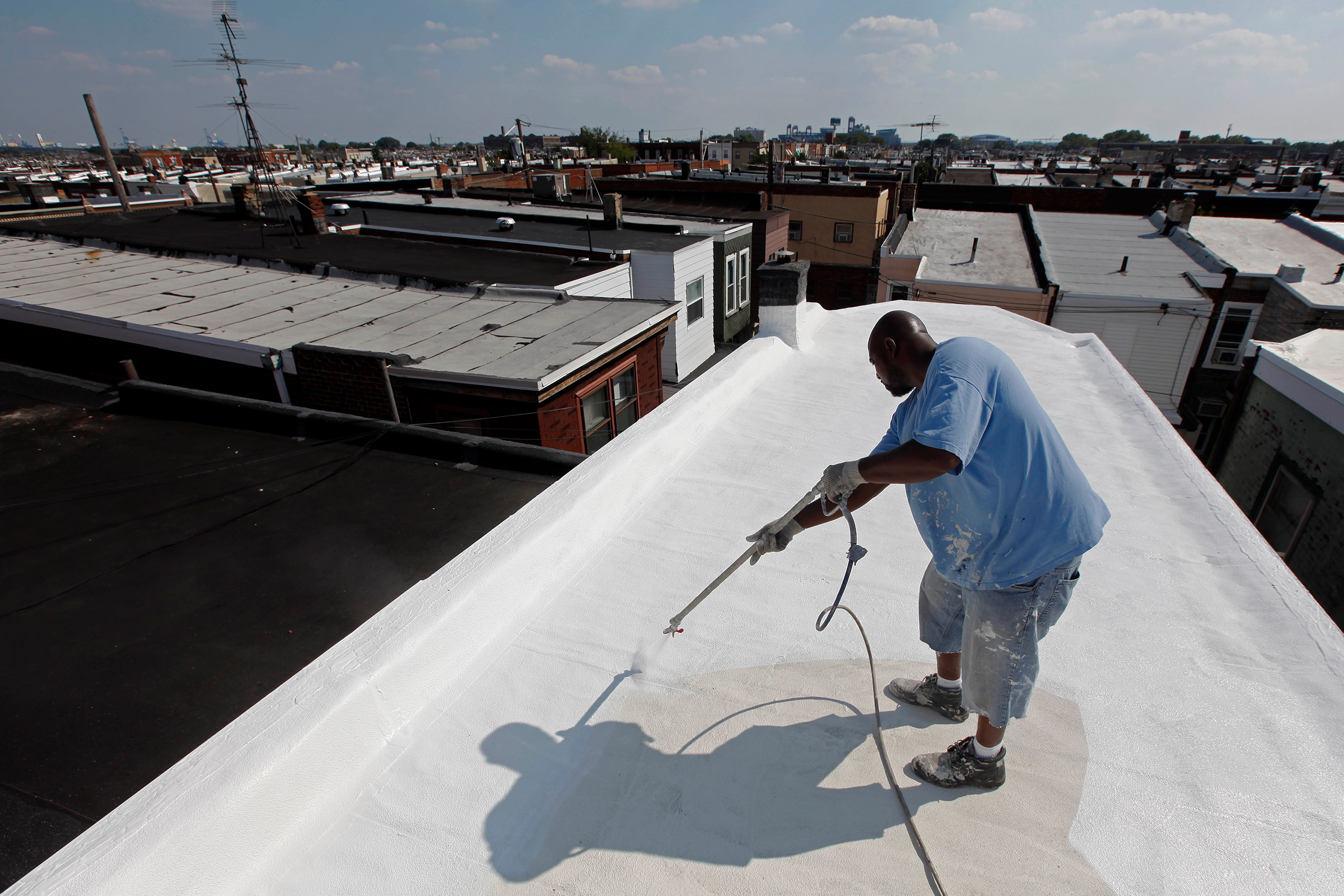 James Peterson with Bio Neighbors applies a coating of Acrymax to the roof of a row home in Philadelphia in August 2010. The idea of painting roofs white has become something of a social movement, one that many believe could be a huge help in stopping global warming.