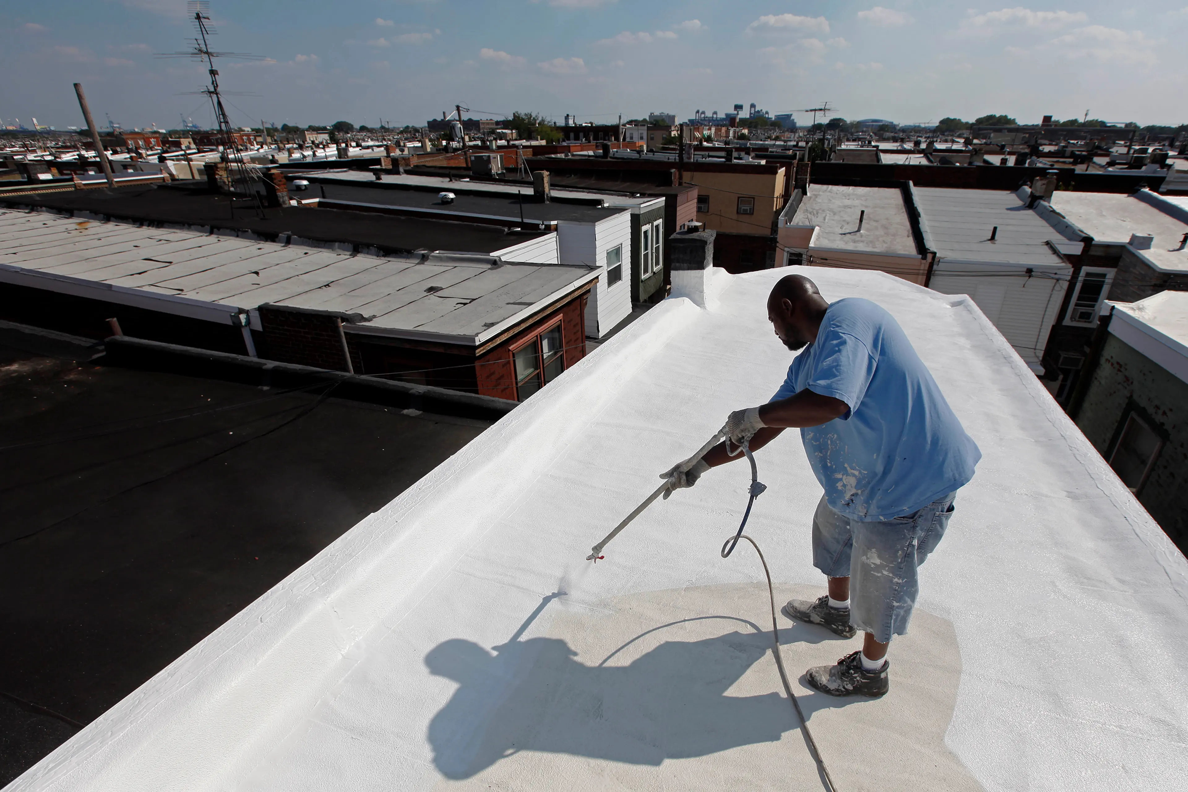 James Peterson with Bio Neighbors applies a coating of Acrymax to the roof of a row home in Philadelphia in August 2010. The idea of painting roofs white has become something of a social movement, one that many believe could be a huge help in stopping global warming.