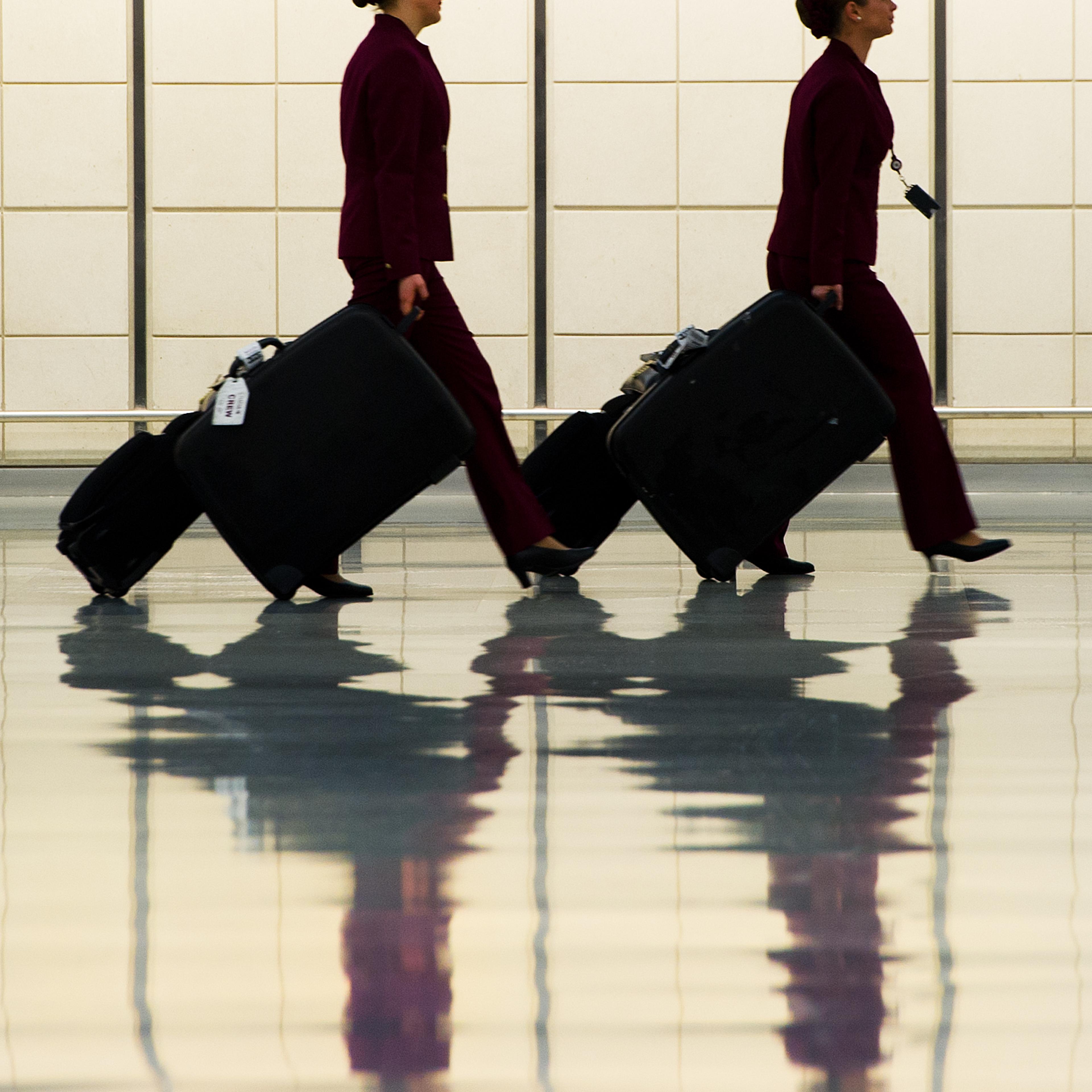 Two flight attendants walk in the luggag