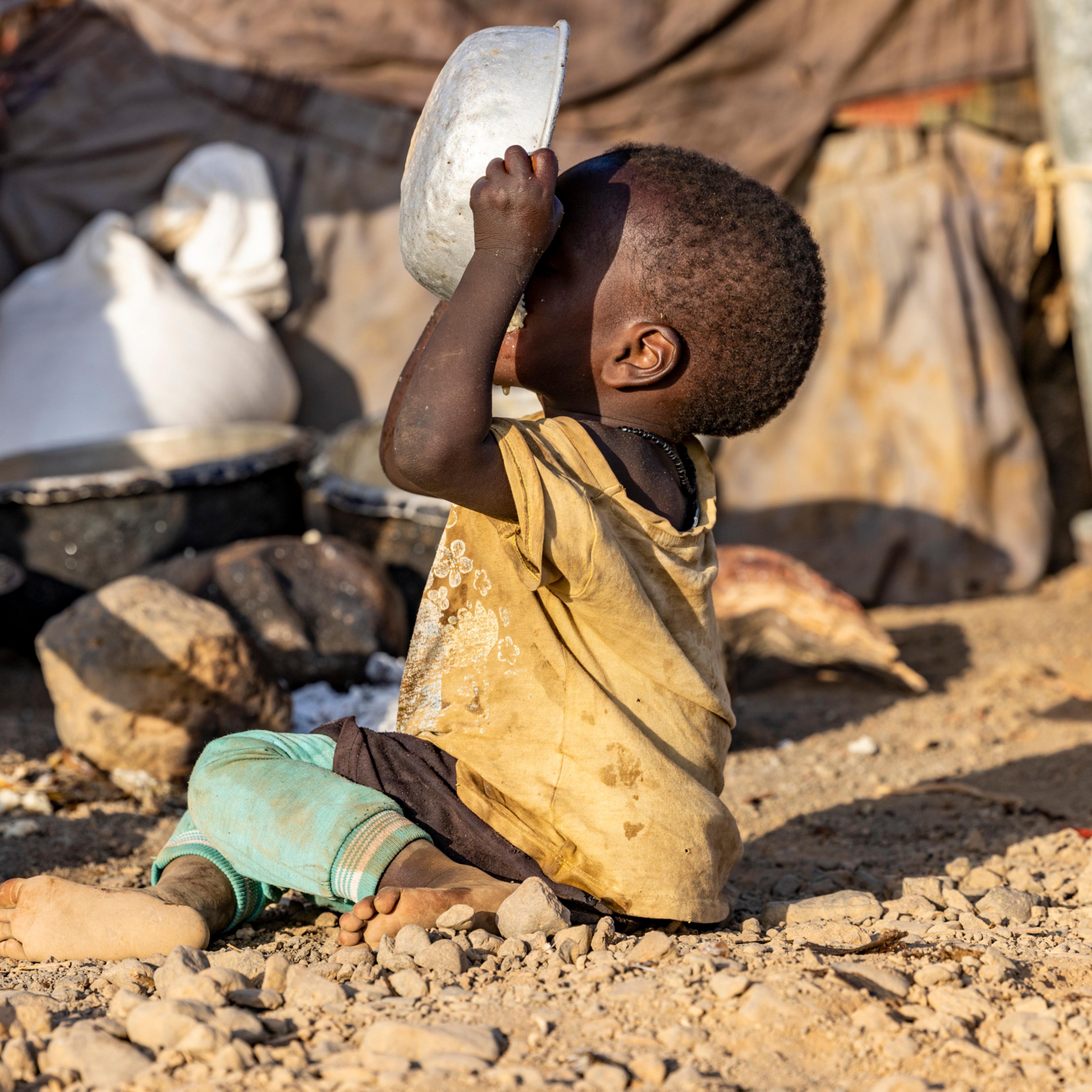 Close-up.Malnourished child due to extreme poverty, drought and climate change. Eating and drinking maize porridge in front of his dwelling. Kenya