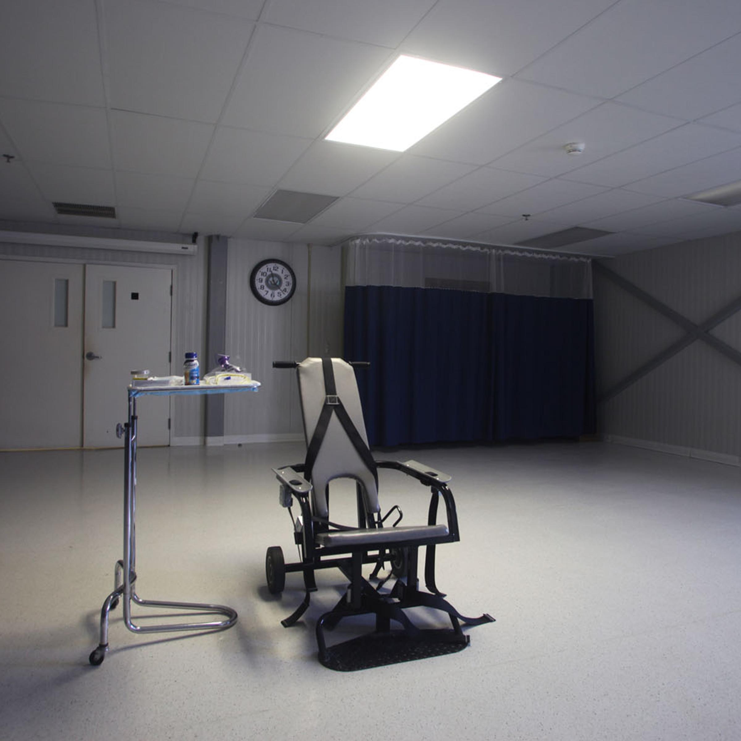 A restraining chair and force-feeding apparatus on display in an empty room of the detainee hospital.