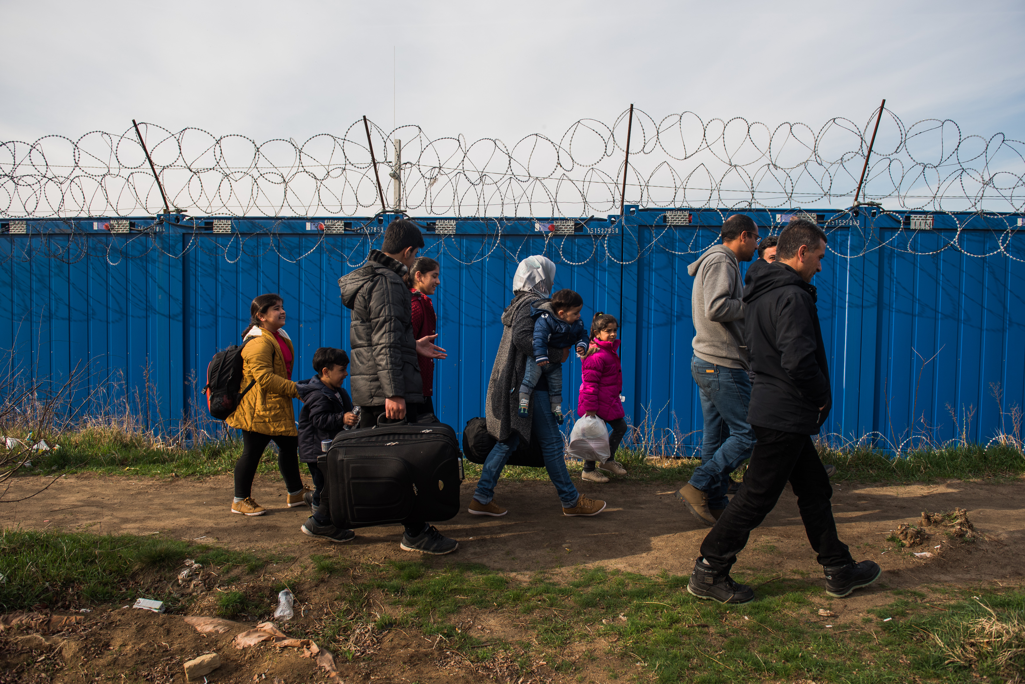 A Syrian family walks towards the gate to cross to Hungary