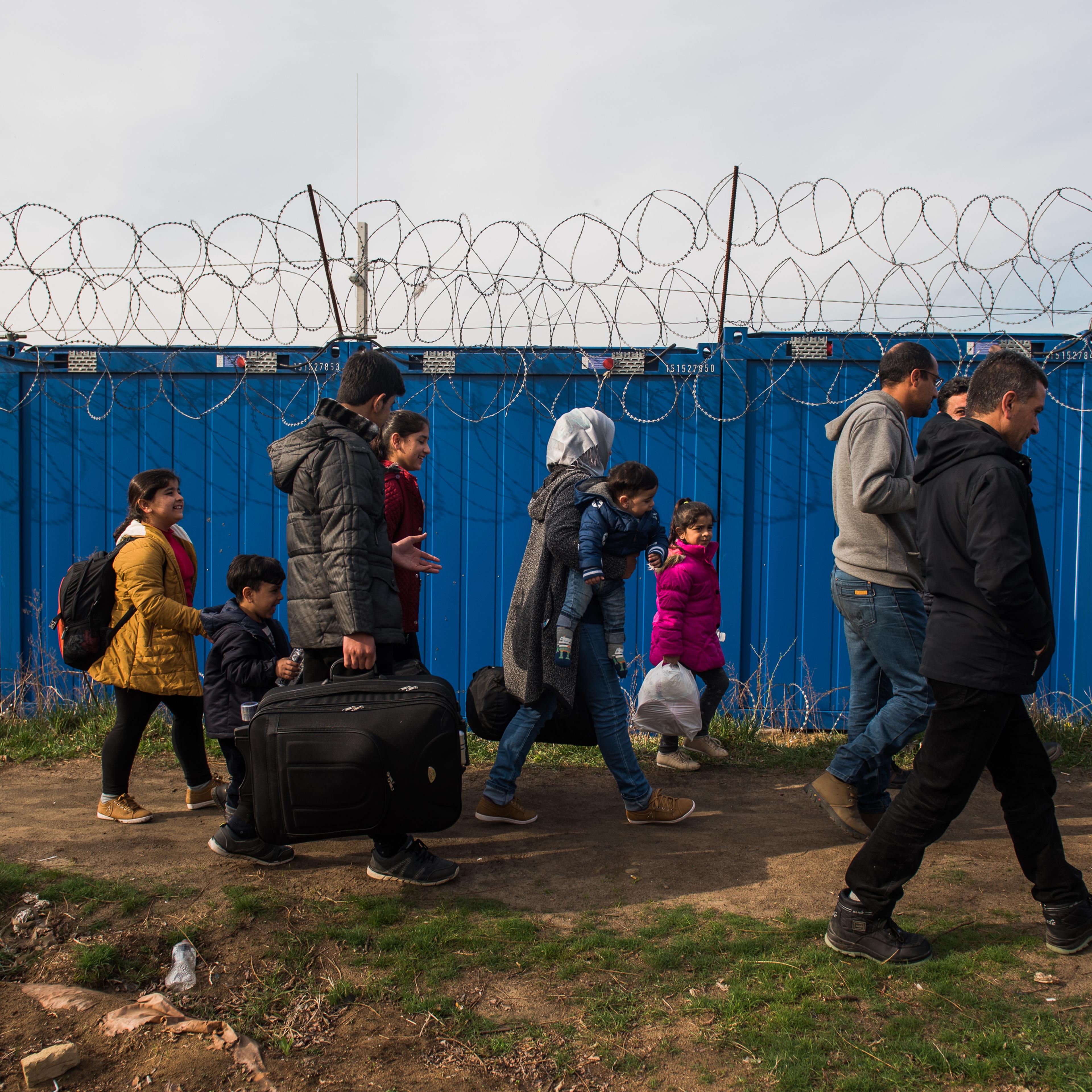 A Syrian family walks towards the gate to cross to Hungary