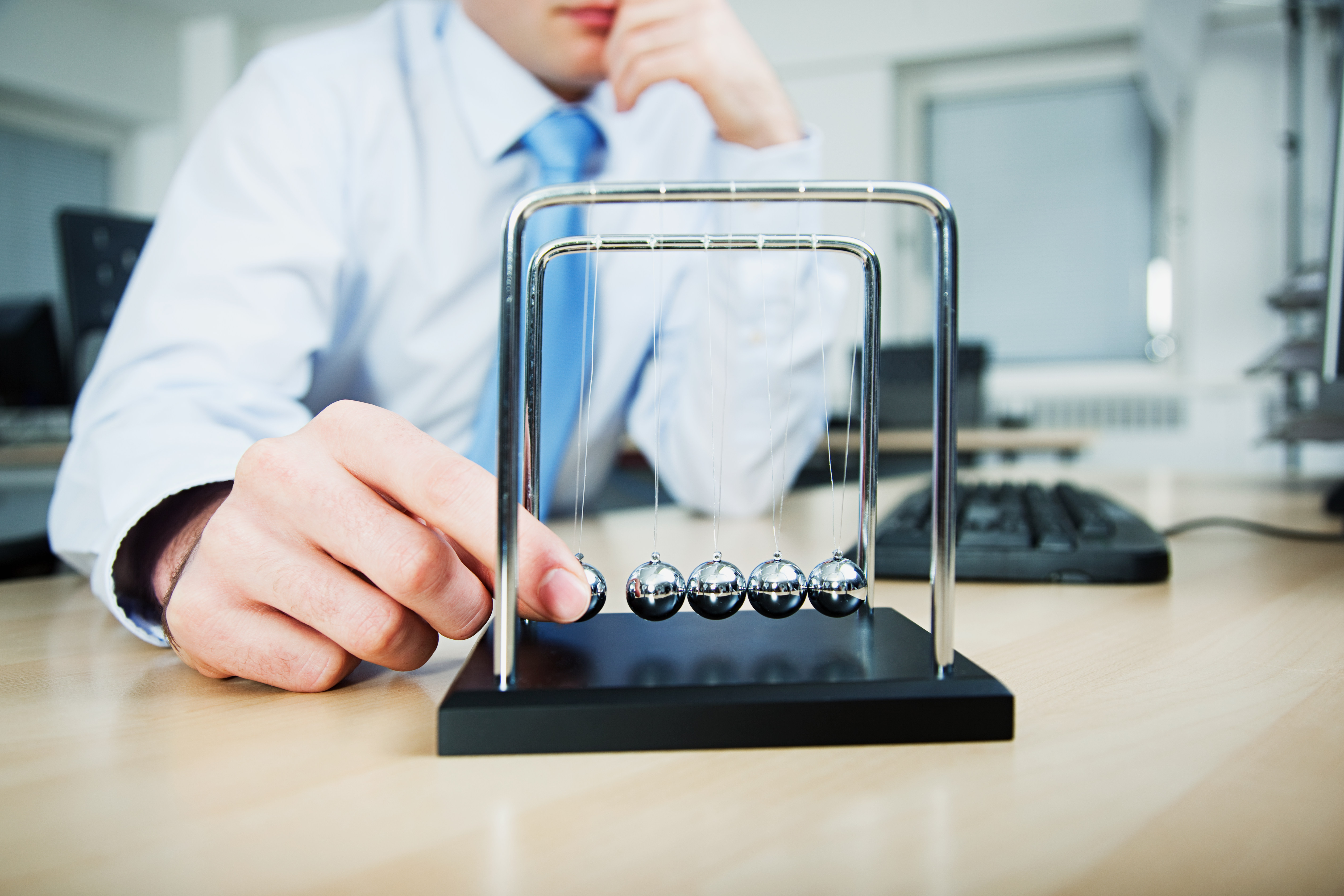 man-playing-with-newtons-cradle
