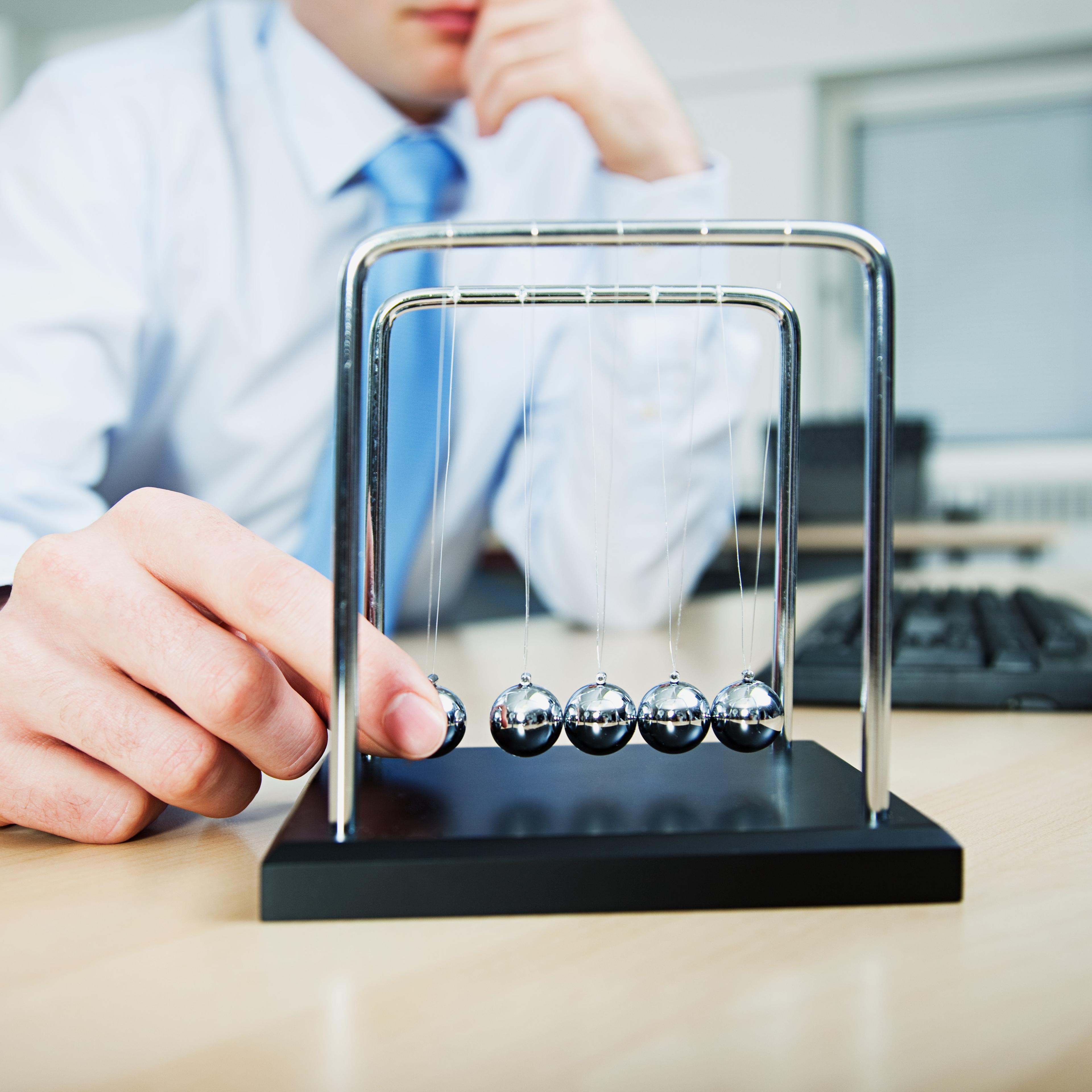 man-playing-with-newtons-cradle