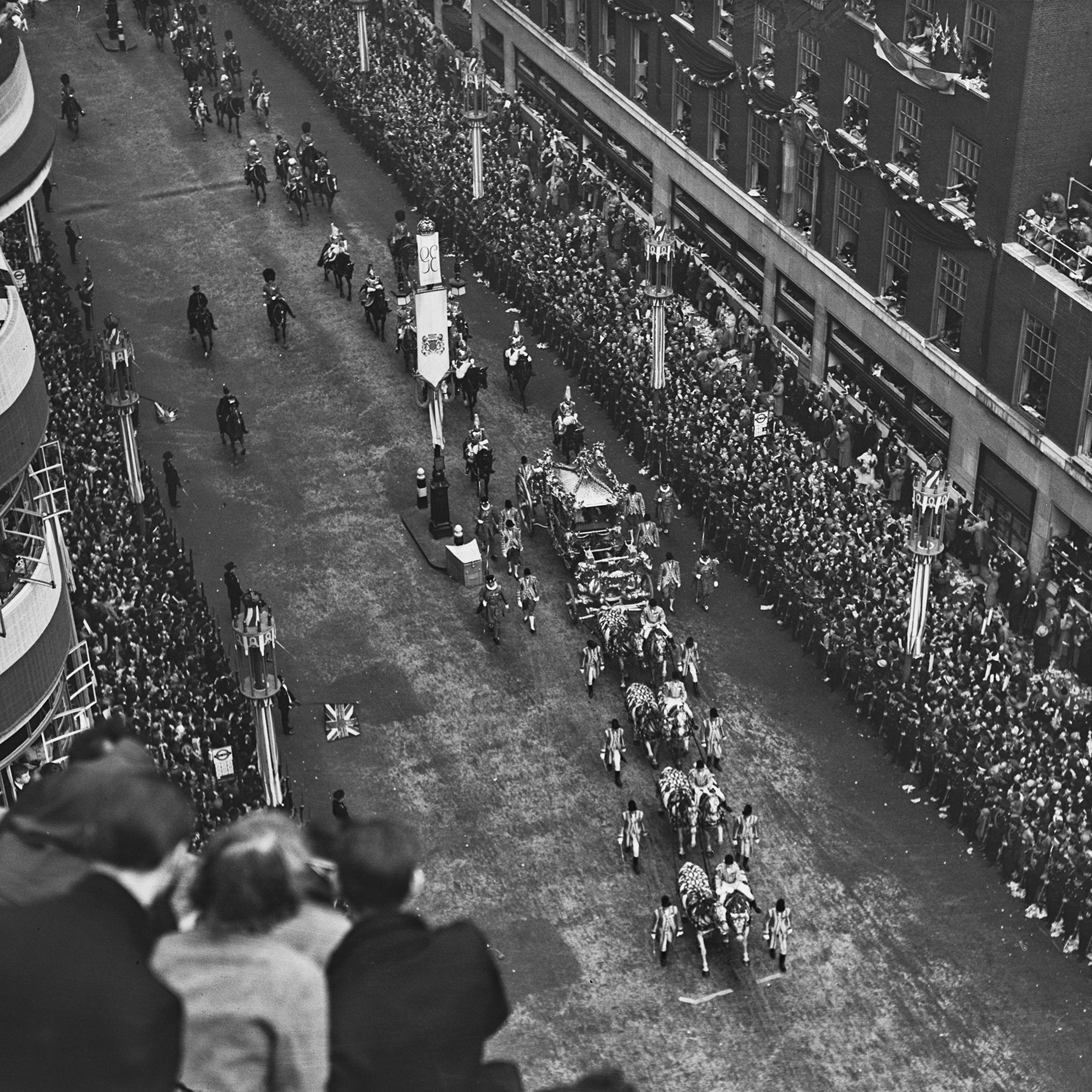 The Gold State Coach, in which George VI and Queen Elizabeth are riding, as it passes along a street lined with crowds of well-wishers en route to their coronation ceremony, held at Westminster Abbey in London, on May 12, 1937.