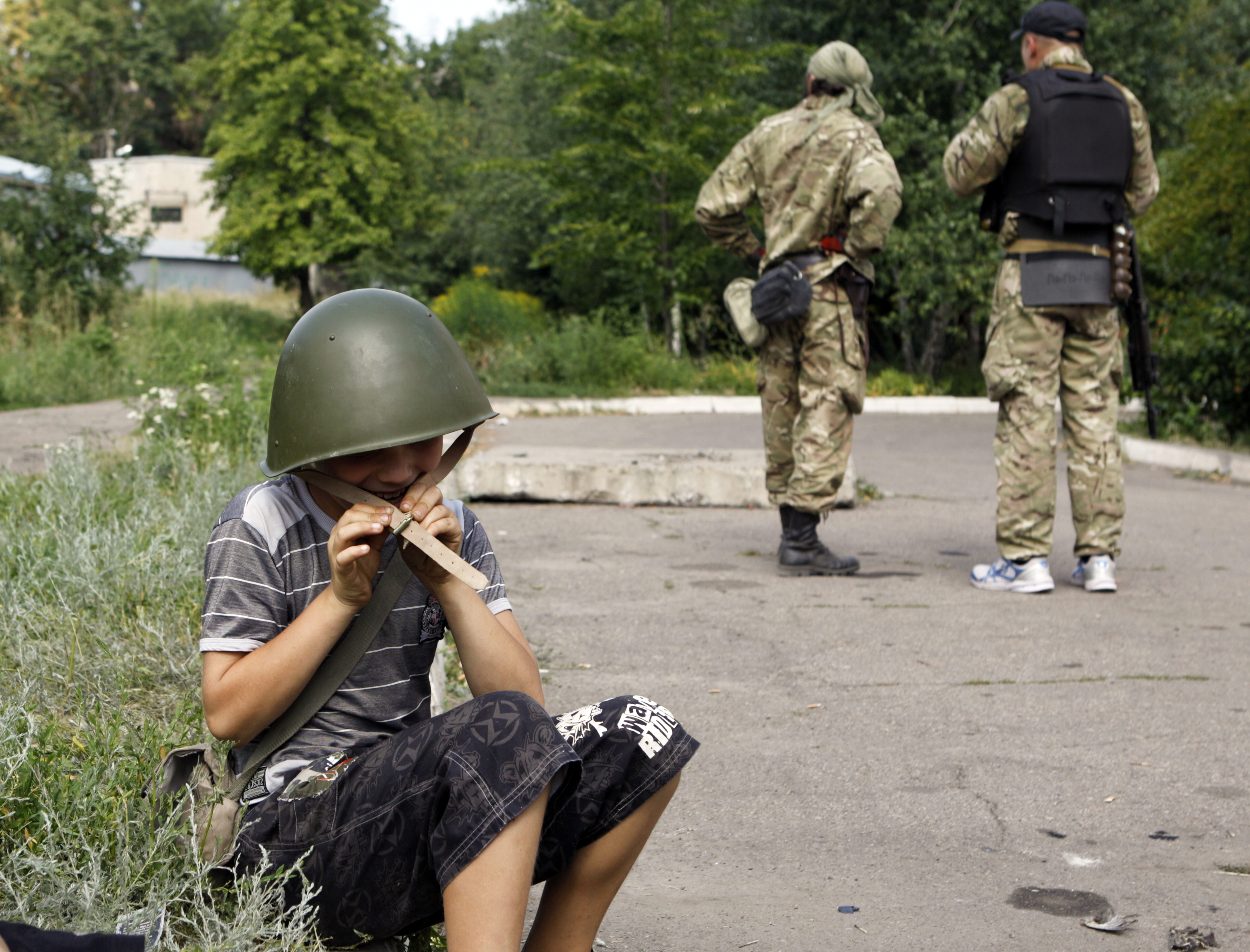A boy plays with a helmet given by member of Ukrainian self-defence battalion "Donbass" in eastern Ukrainian town of Popasna