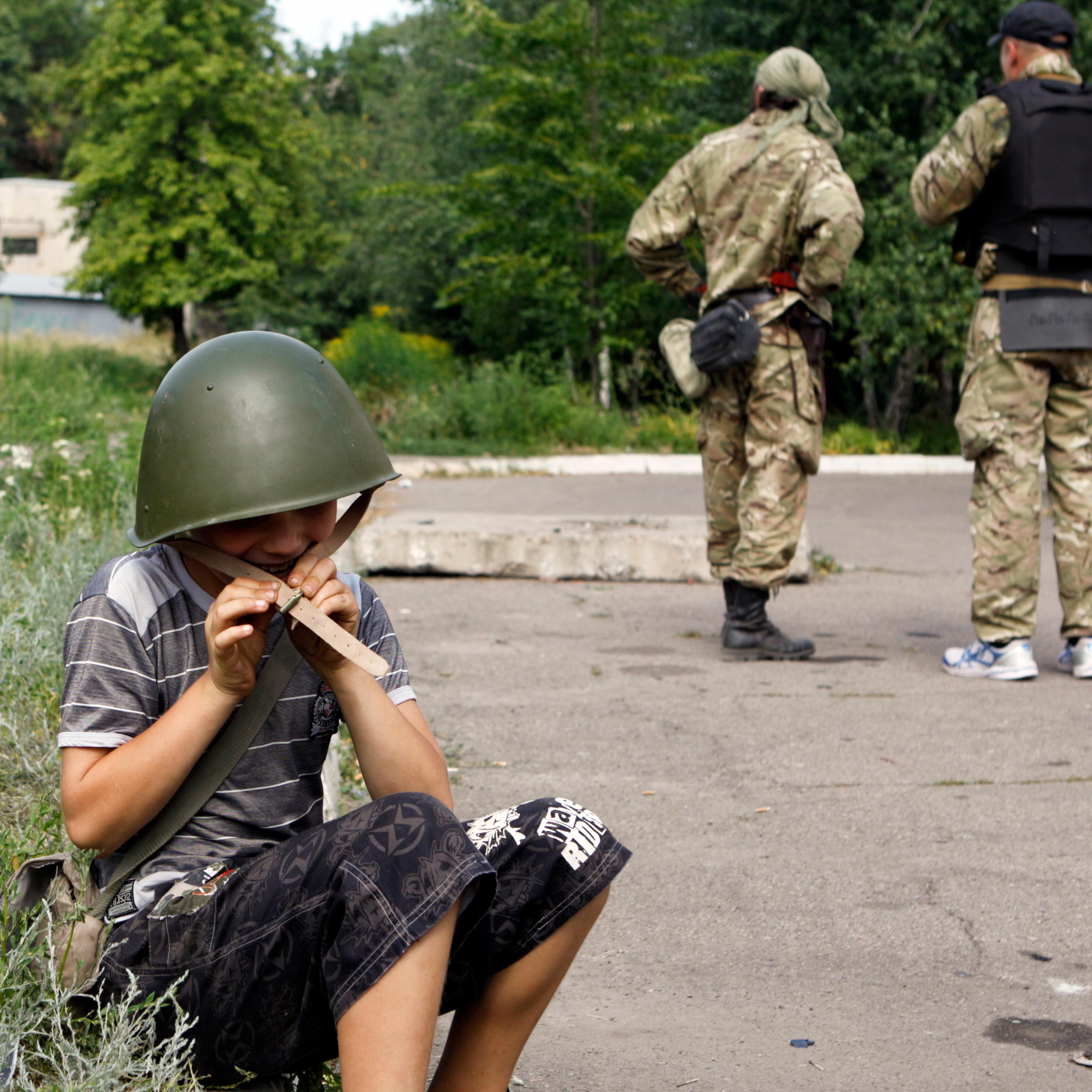 A boy plays with a helmet given by member of Ukrainian self-defence battalion "Donbass" in eastern Ukrainian town of Popasna