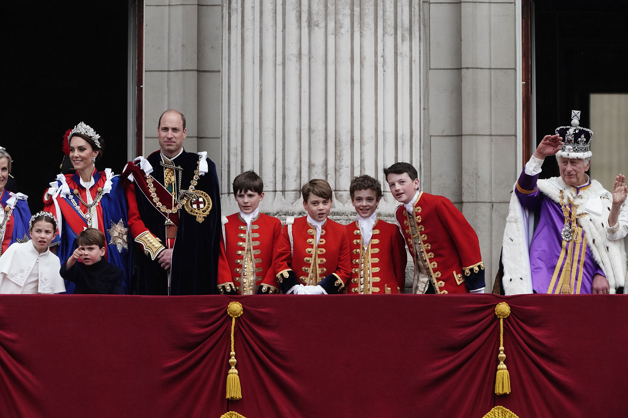 Princess Charlotte, the Princess of Wales, Prince Louis, the Prince of Wales, the Pages of Honour including Prince George (centre) and King Charles III on the balcony of Buckingham Palace following the coronation. 