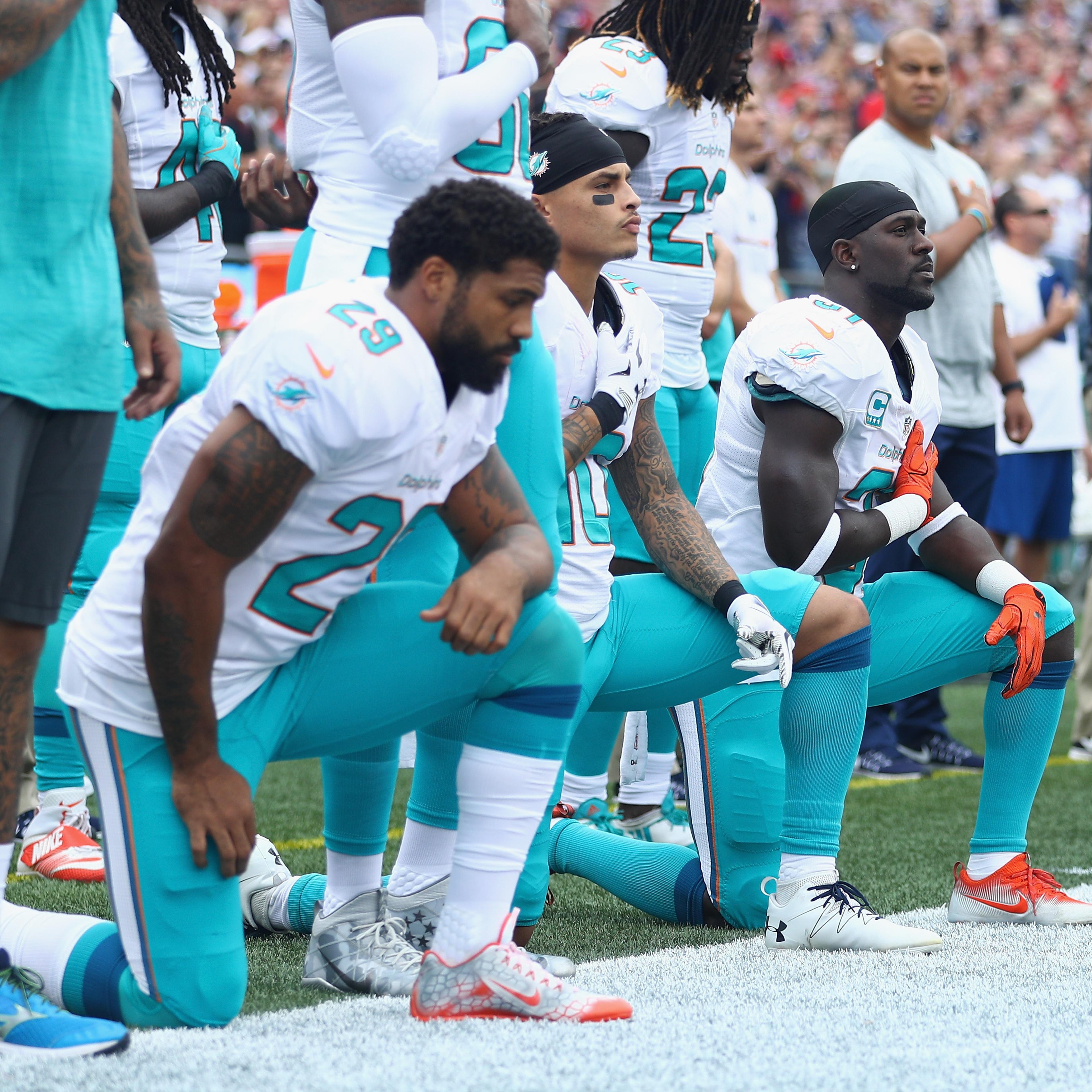 (L-R) Arian Foster #29, Kenny Stills #10 and Michael Thomas #31 of the Miami Dolphins kneel during the national anthem before the game against the New England Patriots at Gillette Stadium in Foxboro, Mass., on Sept. 18, 2016.