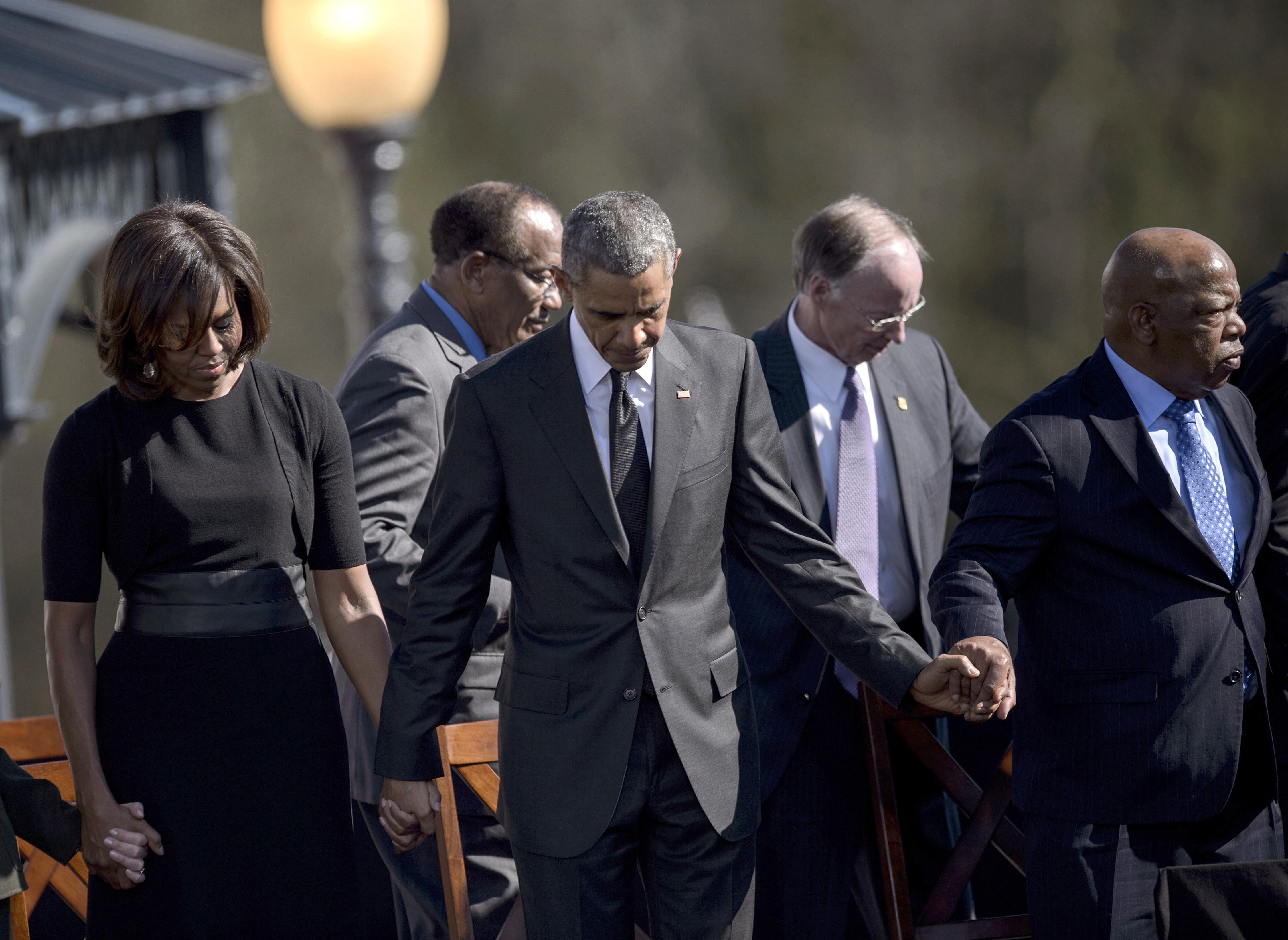 (L-R) US First Lady Michelle Obama, US President Barack Obama, Robert J. Bentley and US Representative John Lewis bow their heads for a prayer at the Edmund Pettus Bridge on March 7, 2015 in Selma, Alabama. Obama marked the 50th anniversary of the Selma 