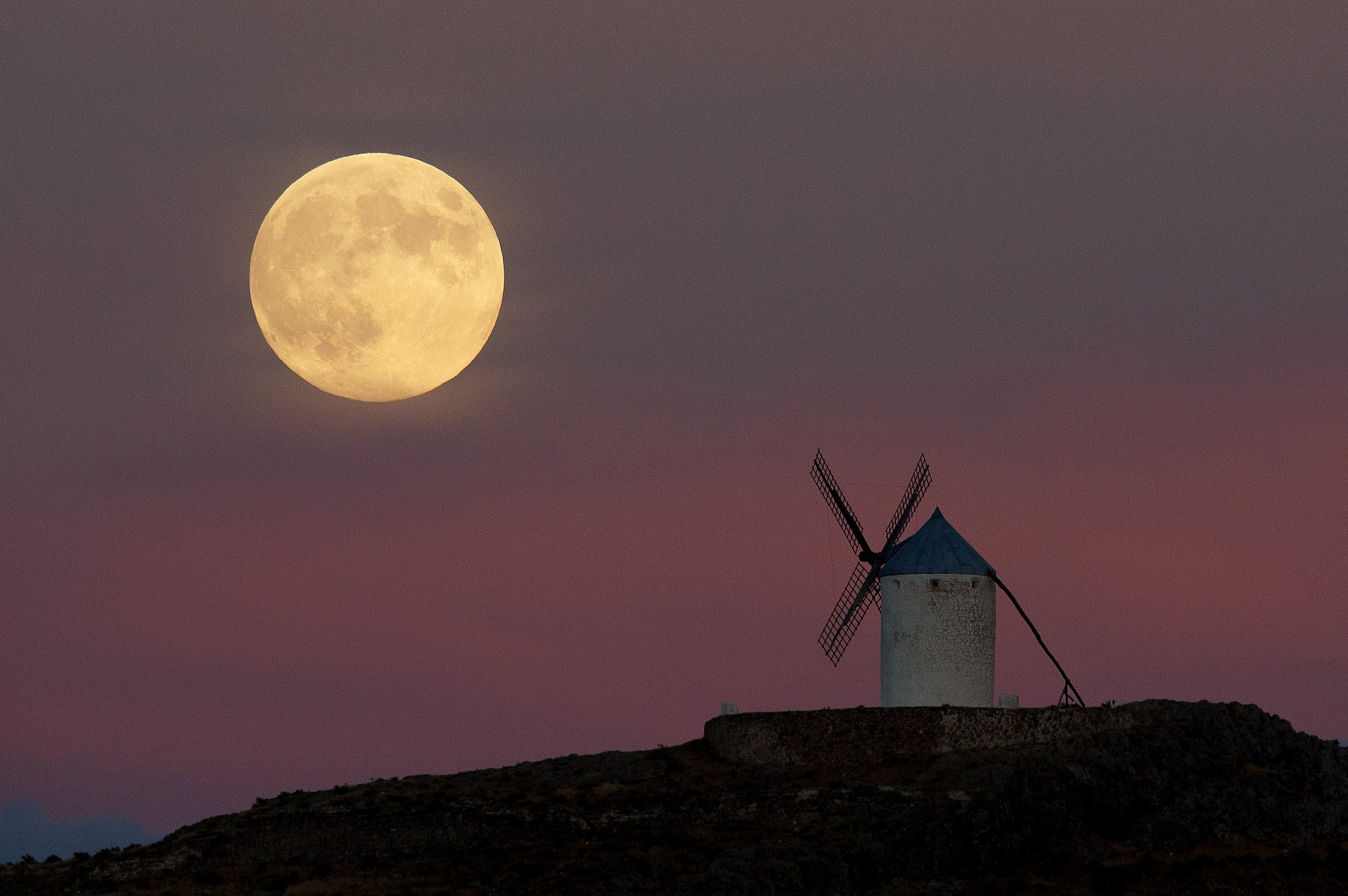 A moon appears behind a windmill a day before the supermoon is full on September 8, 2014 in Consuegra, Toledo province, Spain.