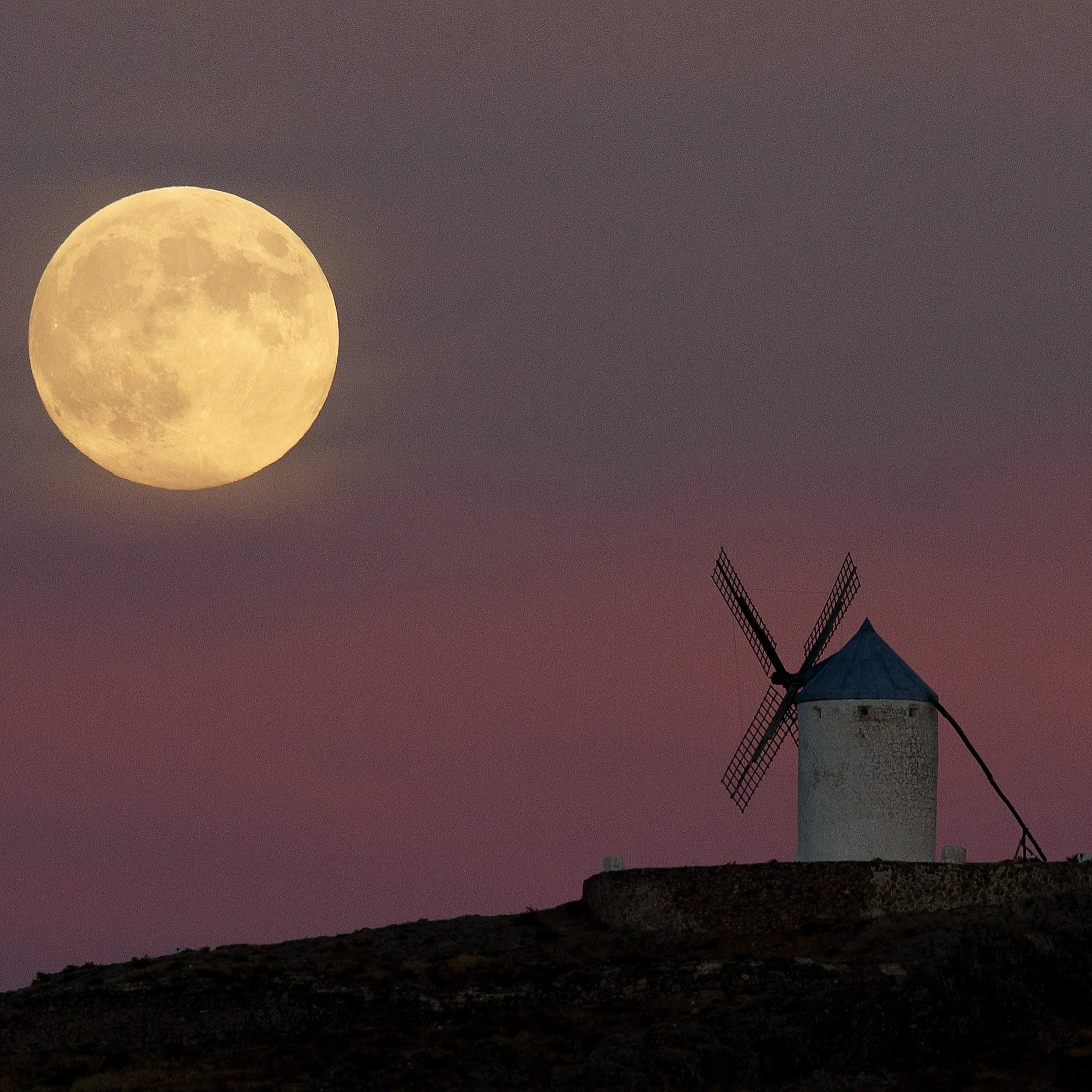A moon appears behind a windmill a day before the supermoon is full on September 8, 2014 in Consuegra, Toledo province, Spain.