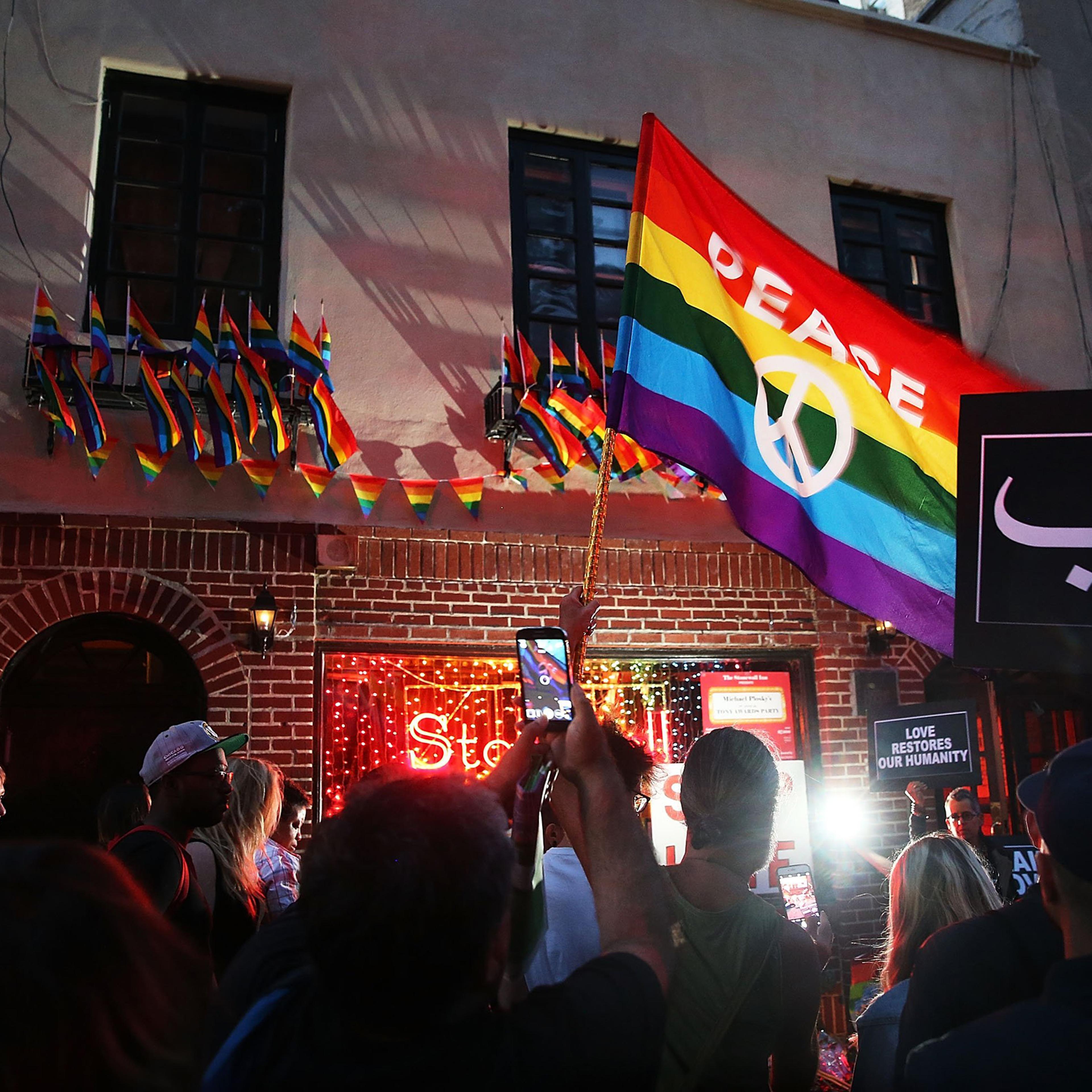 Mourners gather outside of the iconic New York City gay and lesbian bar the Stonewall Inn to light candles,lay flowers and grieve for those killed in Orlando last evening on June 12, 2016.