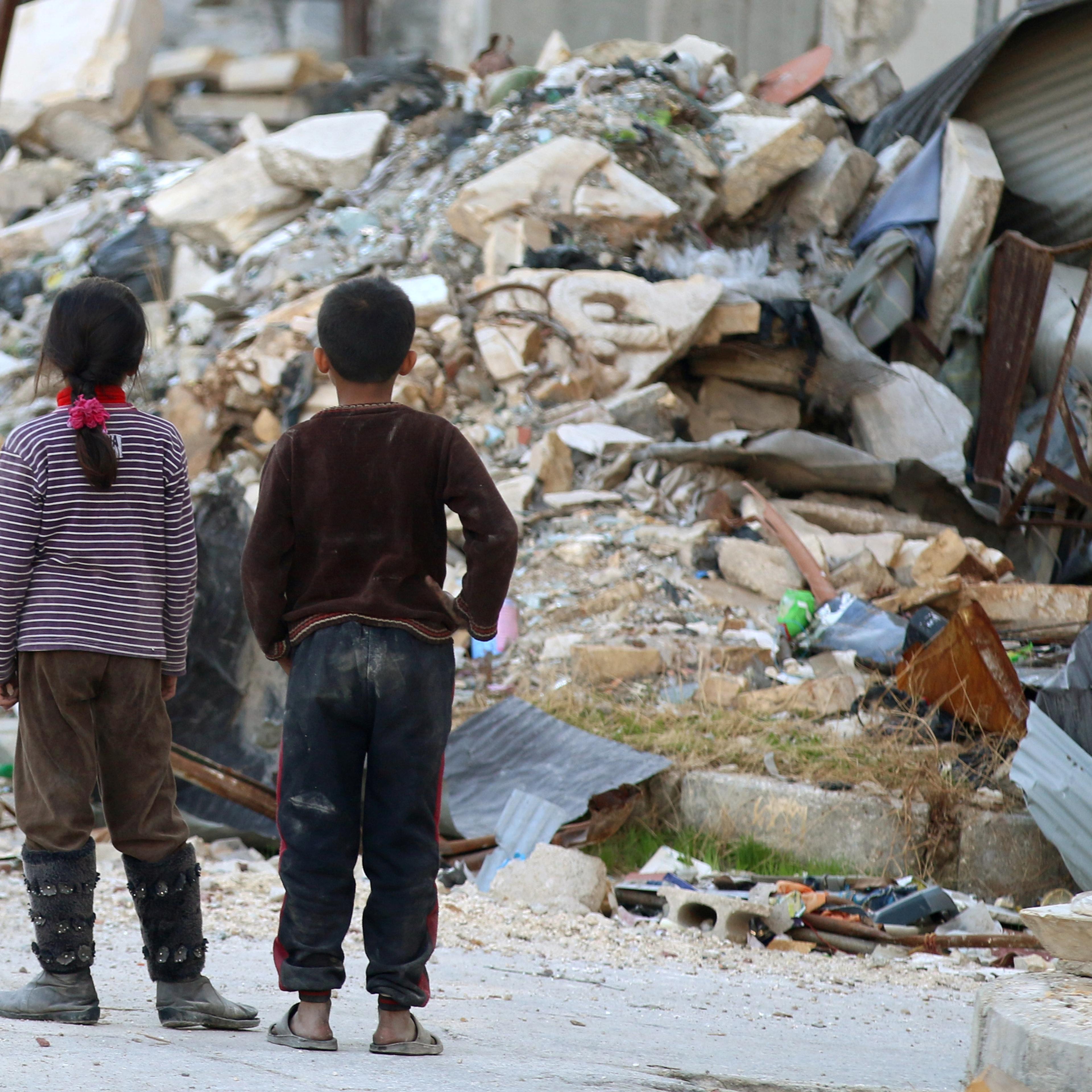 Children inspect rubble of damaged buildings in a rebel-held besieged area in Aleppo