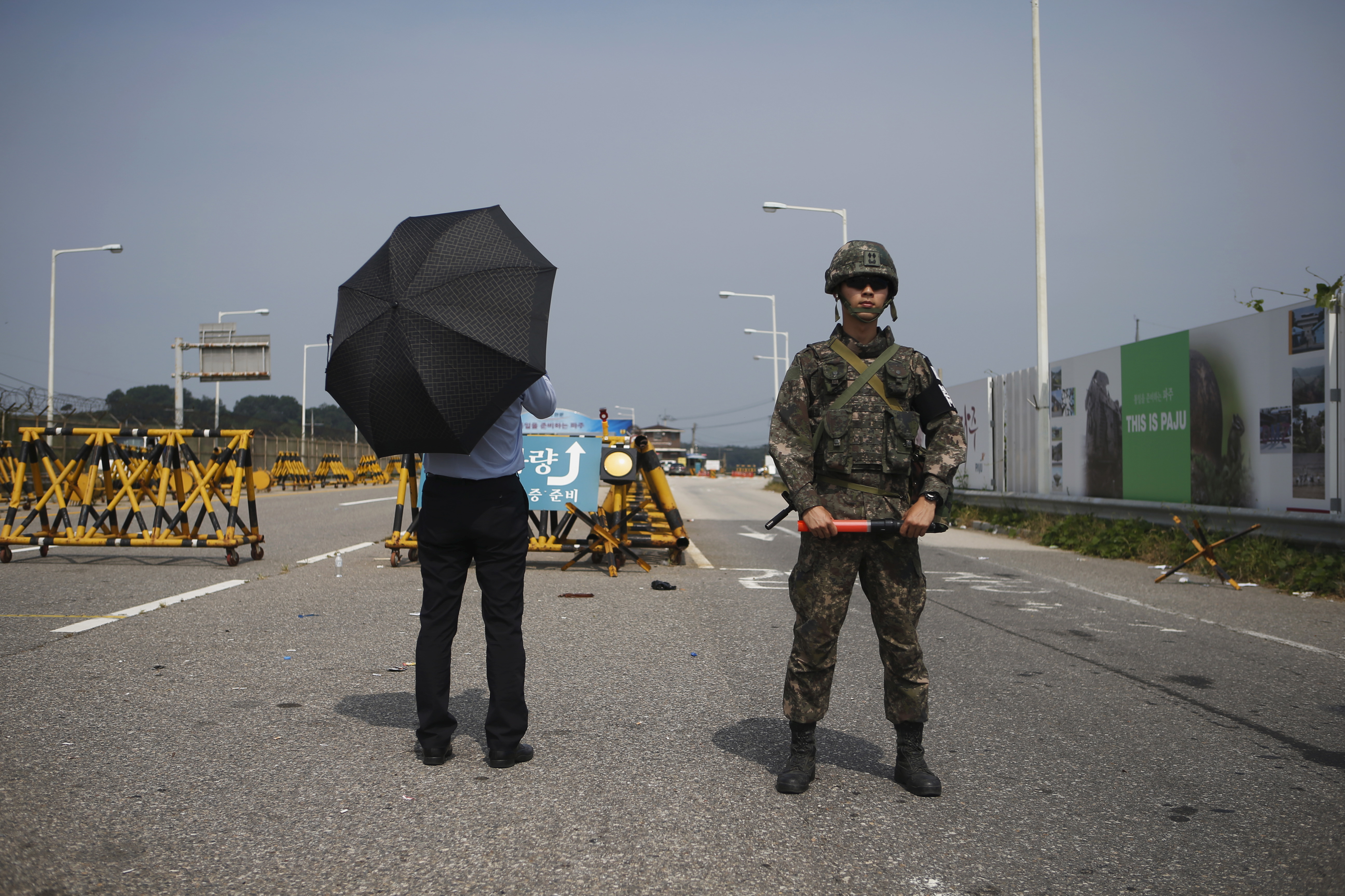 Journalist stands next to South Korean soldier standing guard as he waits for vehicles transporting South Korean delegation at a checkpoint on the Grand Unification Bridge, which leads to truce village Panmunjom, just south of the demilitarized zone