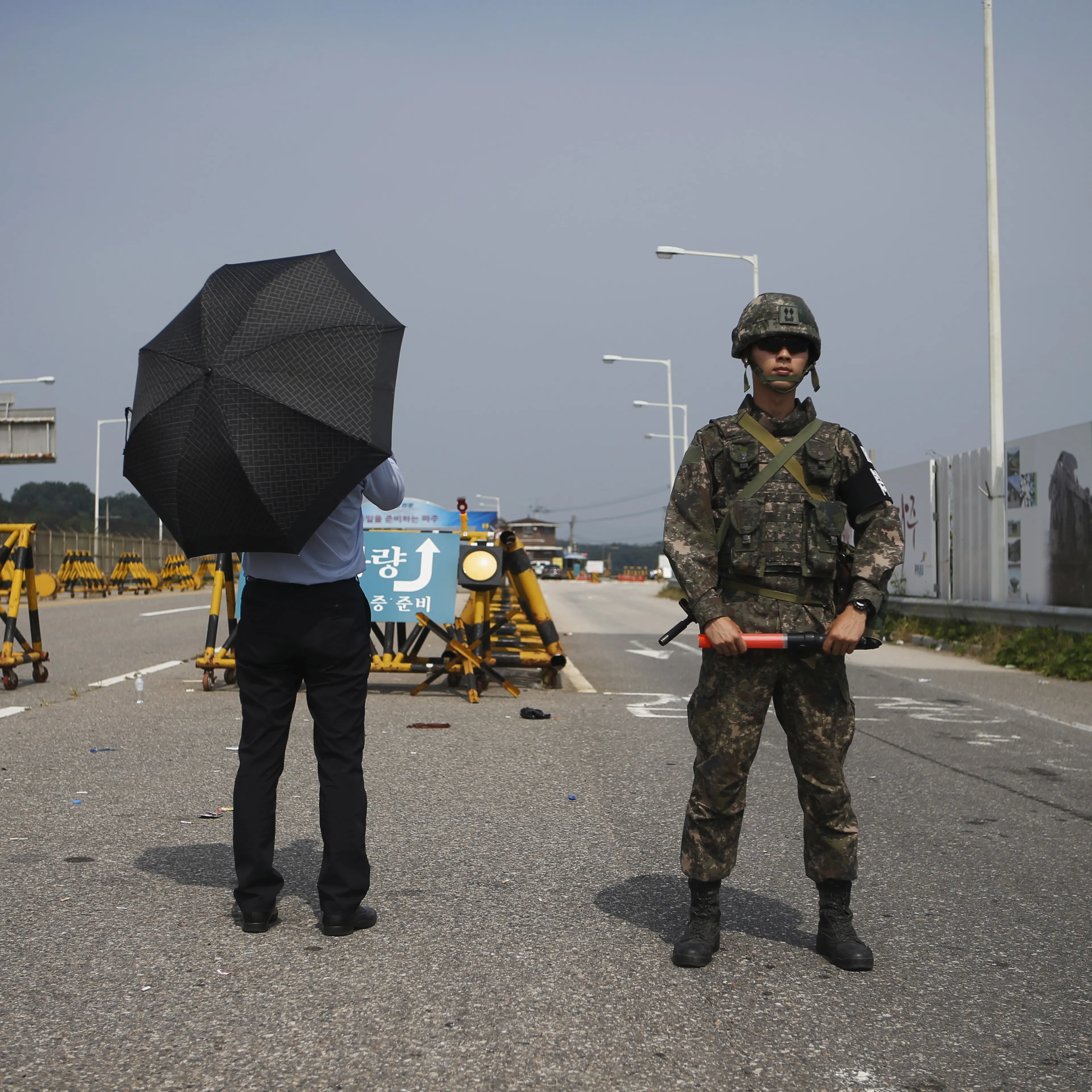 Journalist stands next to South Korean soldier standing guard as he waits for vehicles transporting South Korean delegation at a checkpoint on the Grand Unification Bridge, which leads to truce village Panmunjom, just south of the demilitarized zone