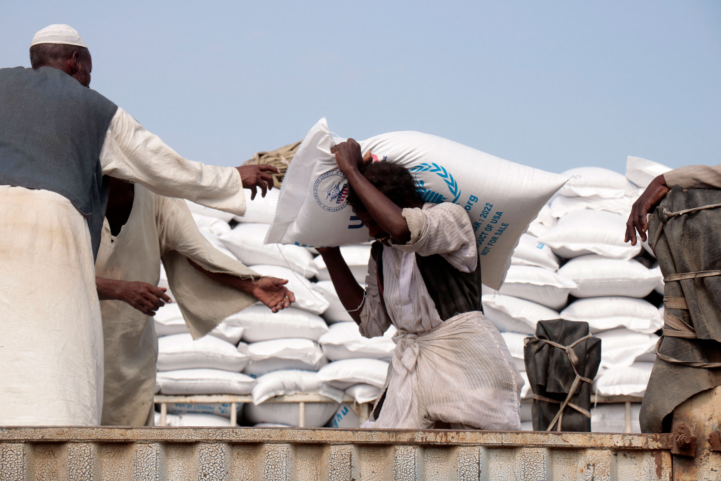 people load sacks of corn provided by US humanitarian aid onto trucks