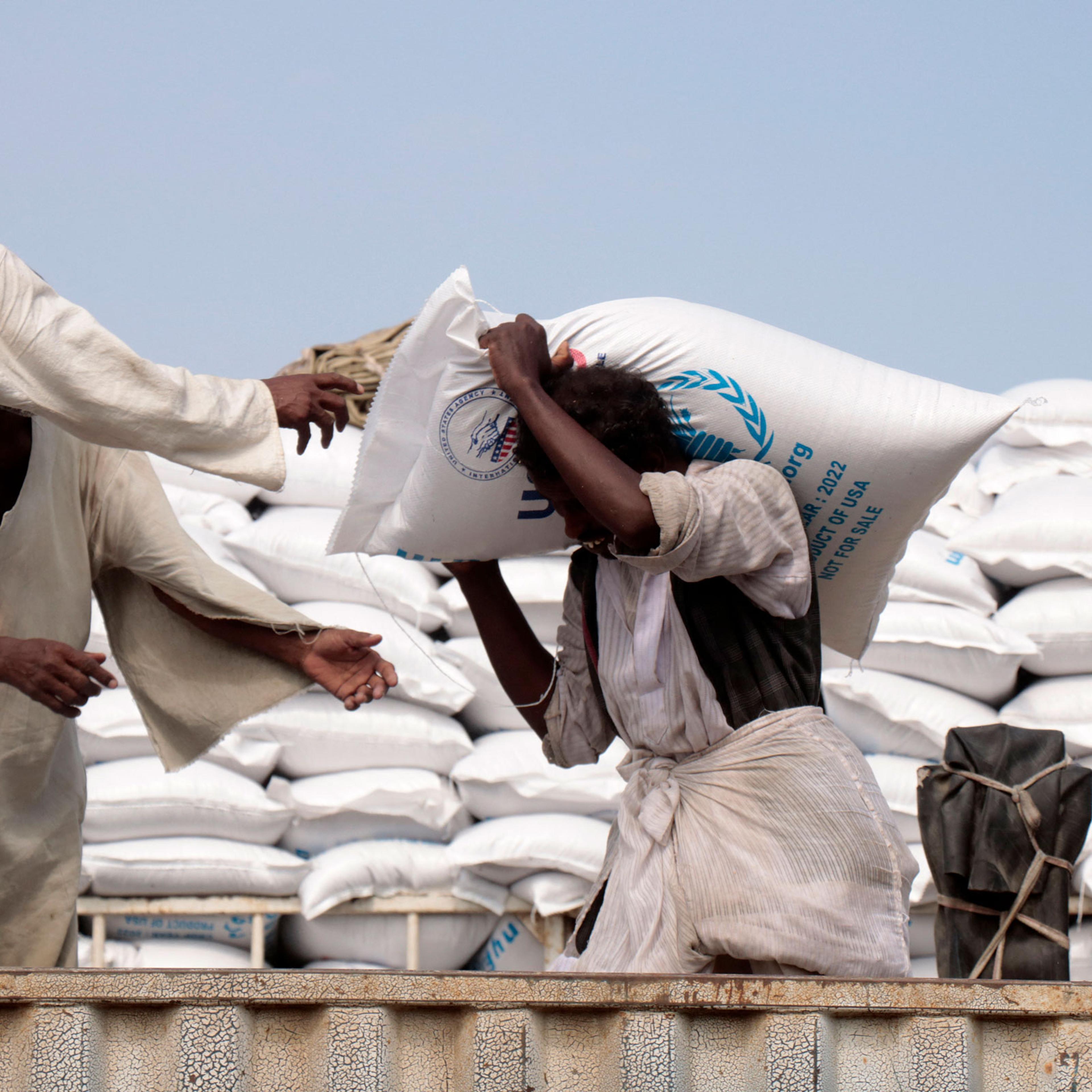 people load sacks of corn provided by US humanitarian aid onto trucks