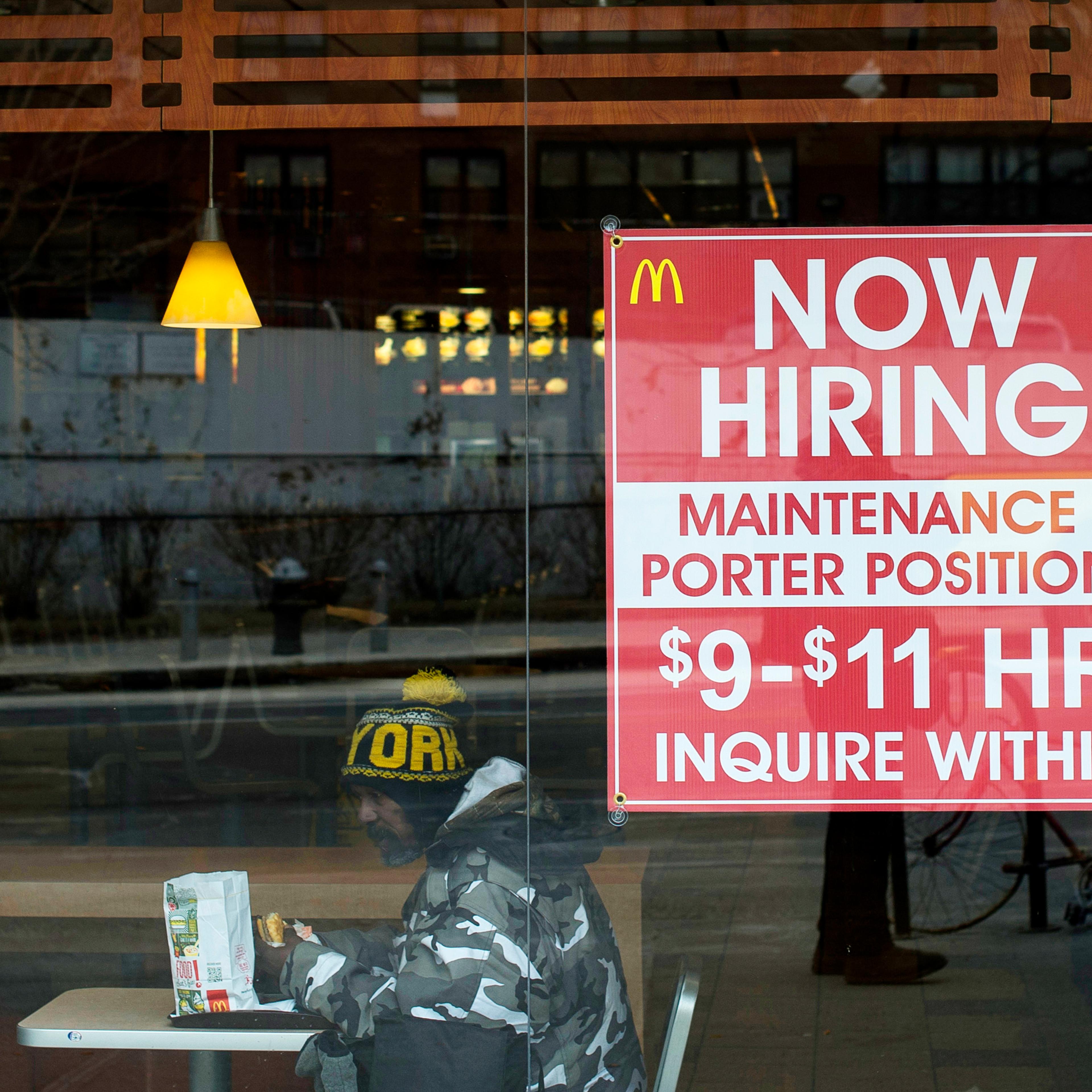 A diner sits next to a help wanted sign at a McDonalds restaurant in the Brooklyn borough of New York, on March 7, 2014.