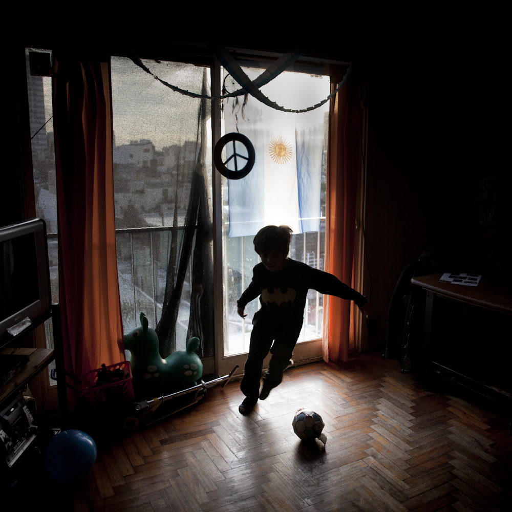 June 24, 2014. A boy plays football at home in his small apartment, with Argentina's flag behind hanging from the balcony. Lots of flags were hung in houses and apartments in Buenos Aires