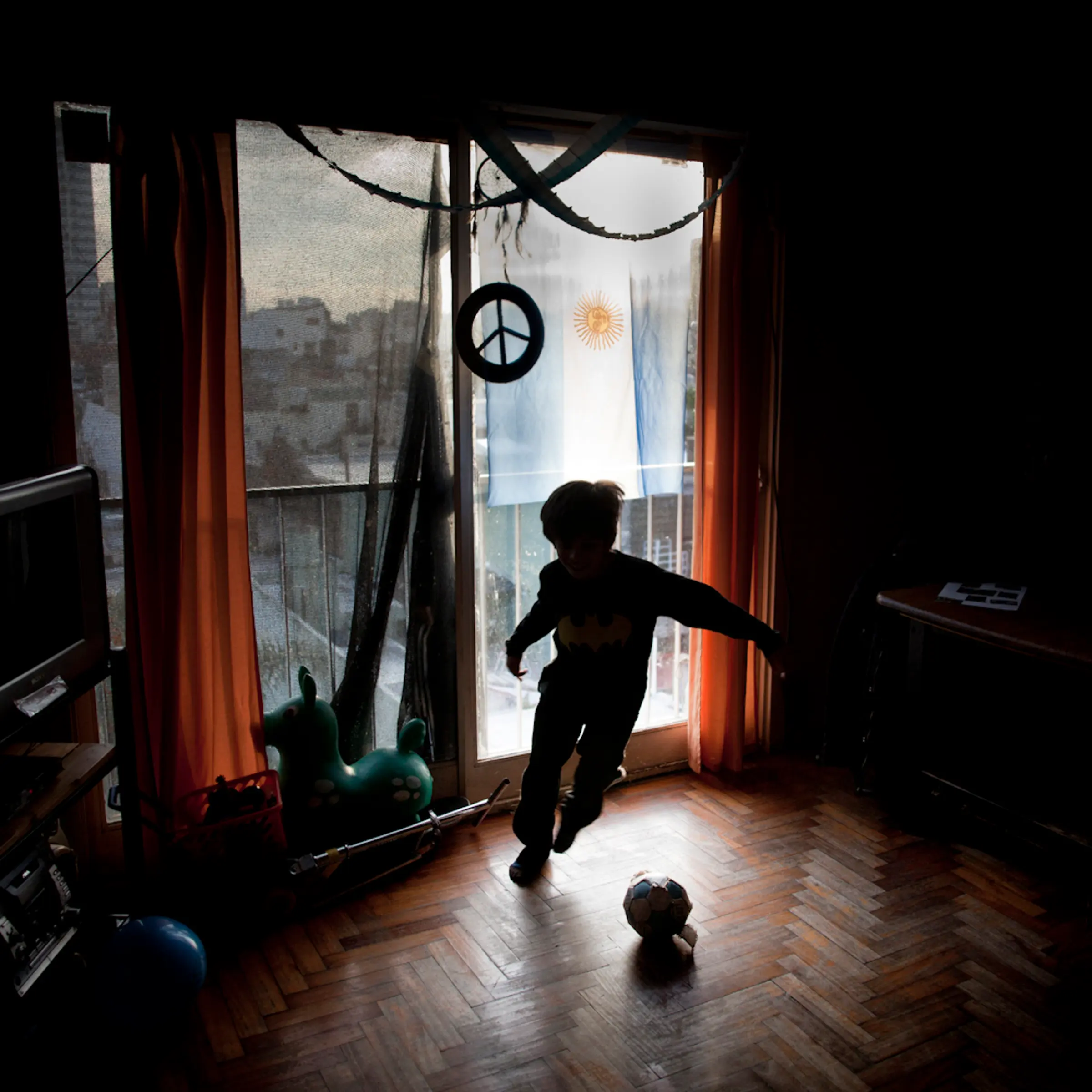 June 24, 2014. A boy plays football at home in his small apartment, with Argentina's flag behind hanging from the balcony. Lots of flags were hung in houses and apartments in Buenos Aires