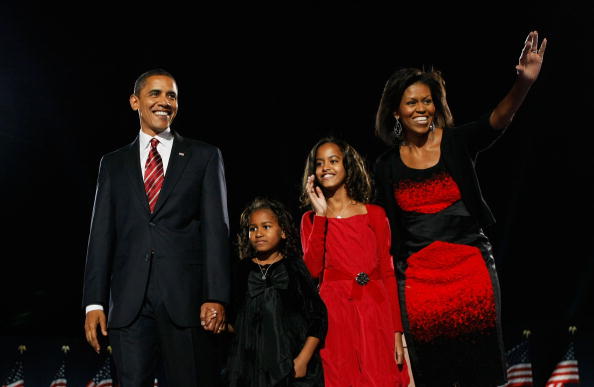 U.S. President elect Barack Obama stands on stage along with his wife Michelle and daughters Malia (red dress) and Sasha (black dress) during an election night gathering in Grant Park on November 4, 2008 in Chicago, Illinois.