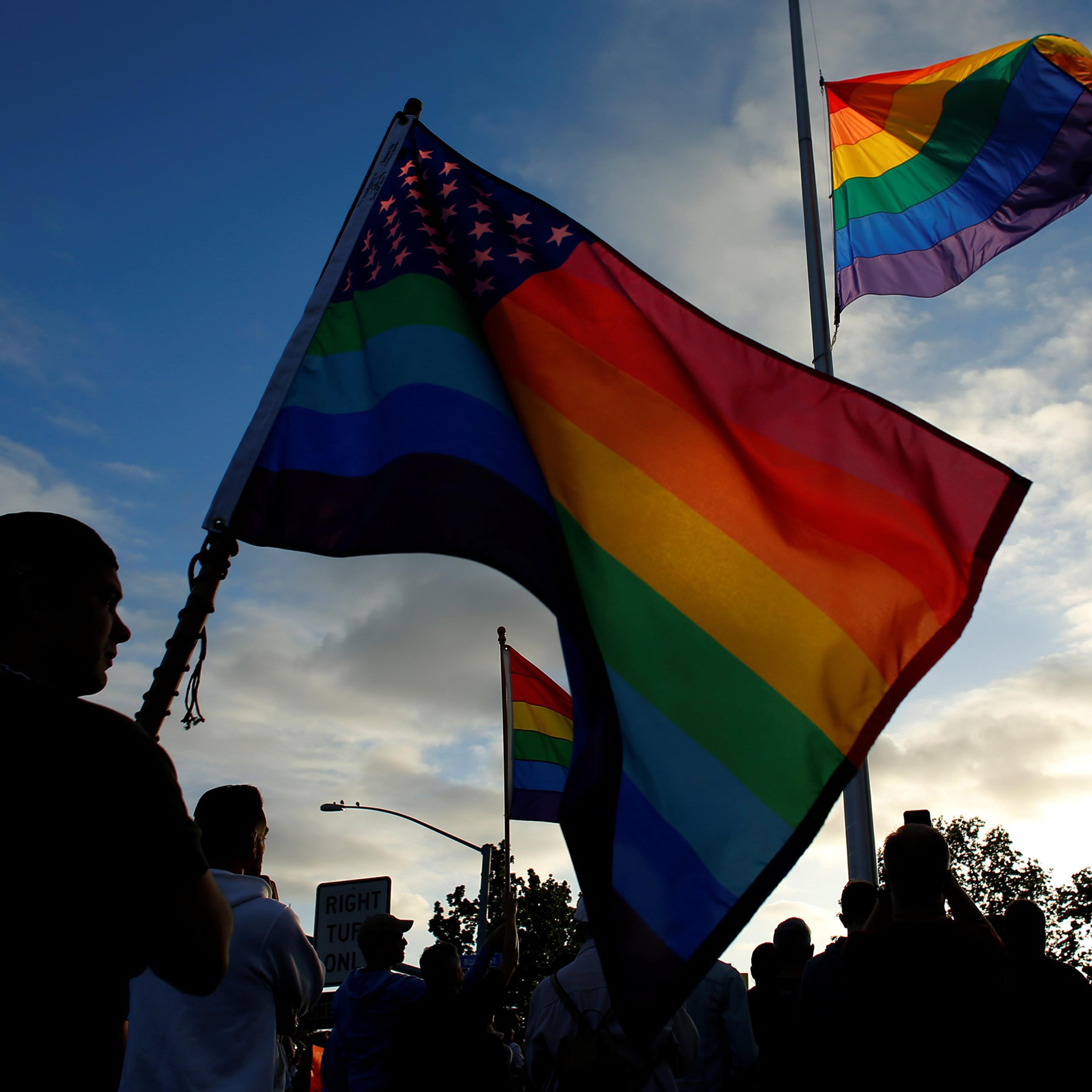 Mourners gather under an LGBT pride flag flying at half-mast for a candlelight vigil in remembrance for mass shooting victims in Orlando, from San Diego, June 12, 2016.