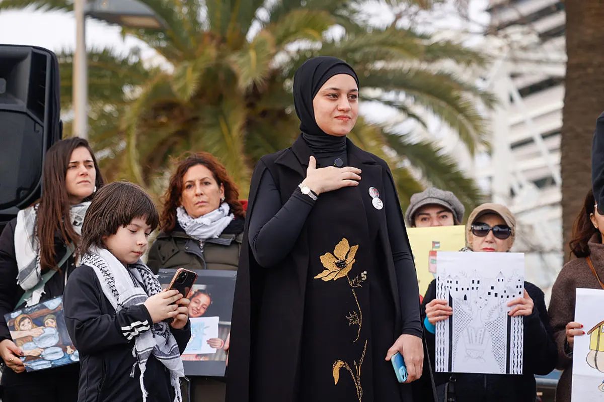 Wesam Hamada, Hind Rajab's mother, helps unfurl a giant canvas portrait of Hind in Barcelona