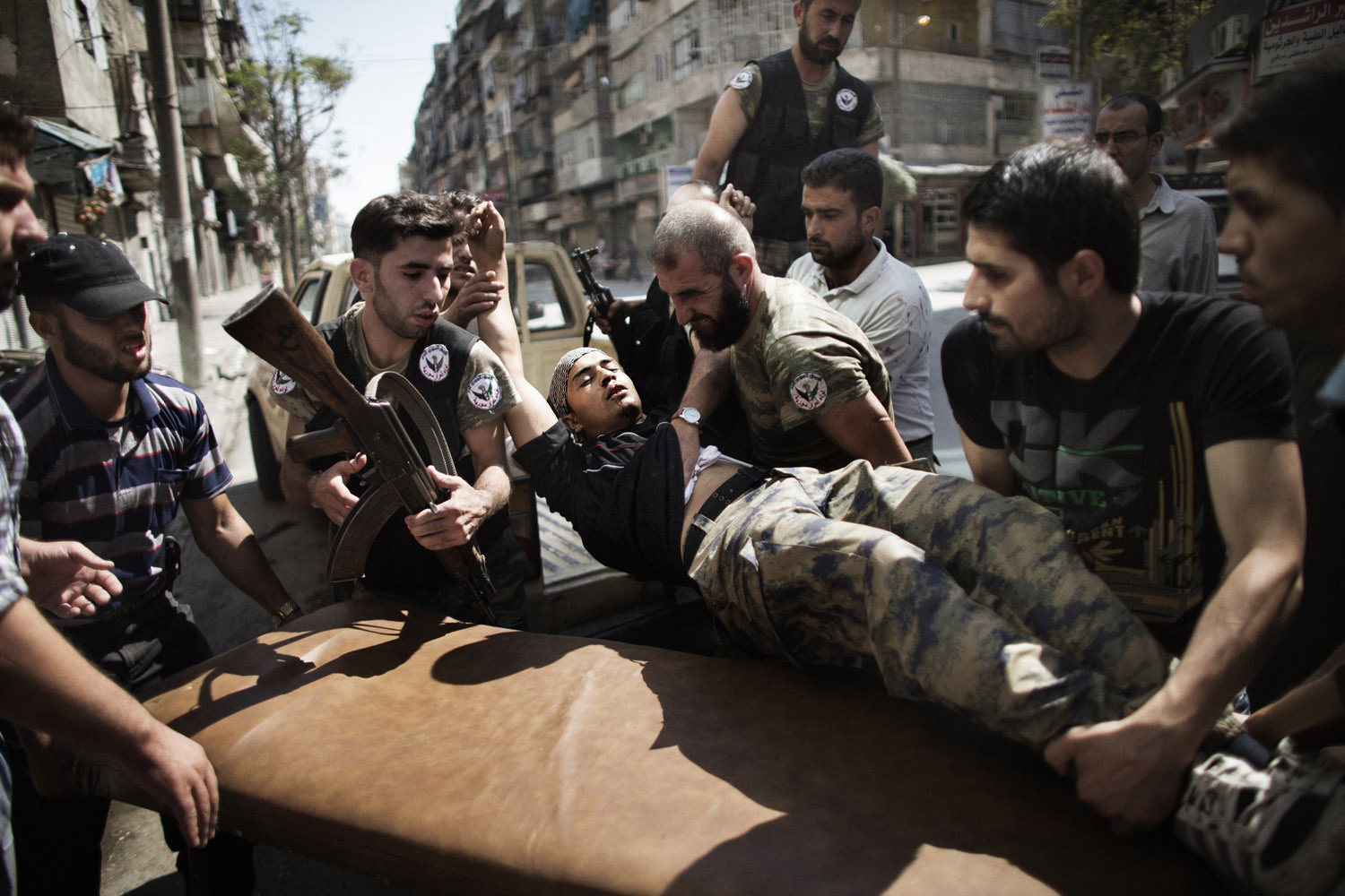 Sept. 18, 2012. Syrian rebels help a wounded comrade who survived a Syrian army strike outside a hospital in the northern city of Aleppo.