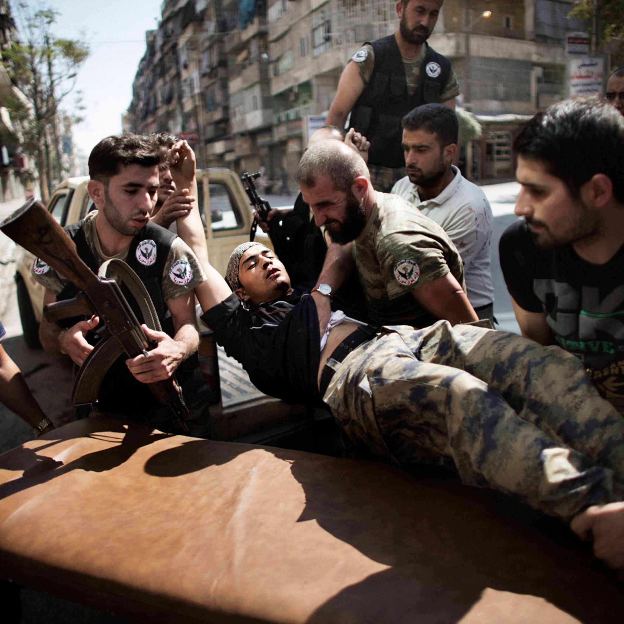 Sept. 18, 2012. Syrian rebels help a wounded comrade who survived a Syrian army strike outside a hospital in the northern city of Aleppo.